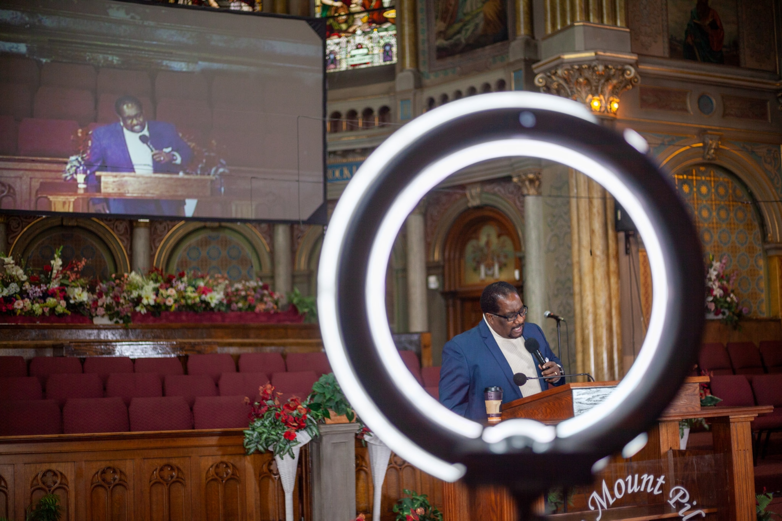 a preacher framed by a ring light as he is being filmed