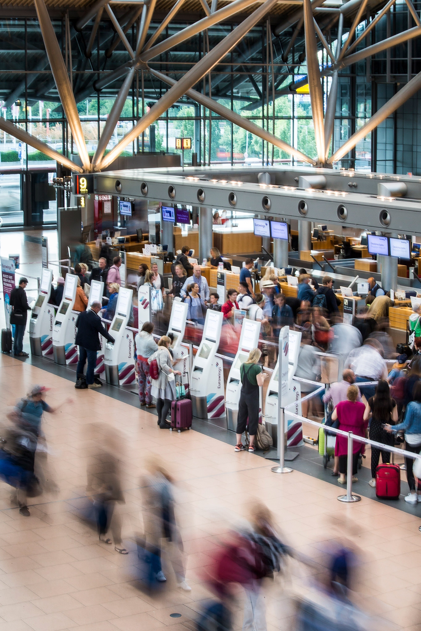 People rushing through the terminal as others stand in line at counter.