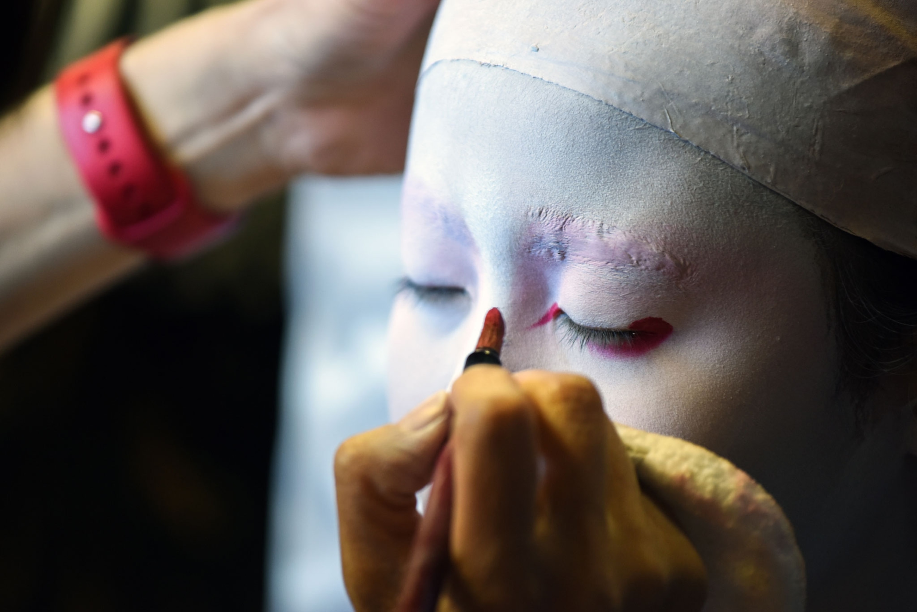 a student applies red makeup to their face