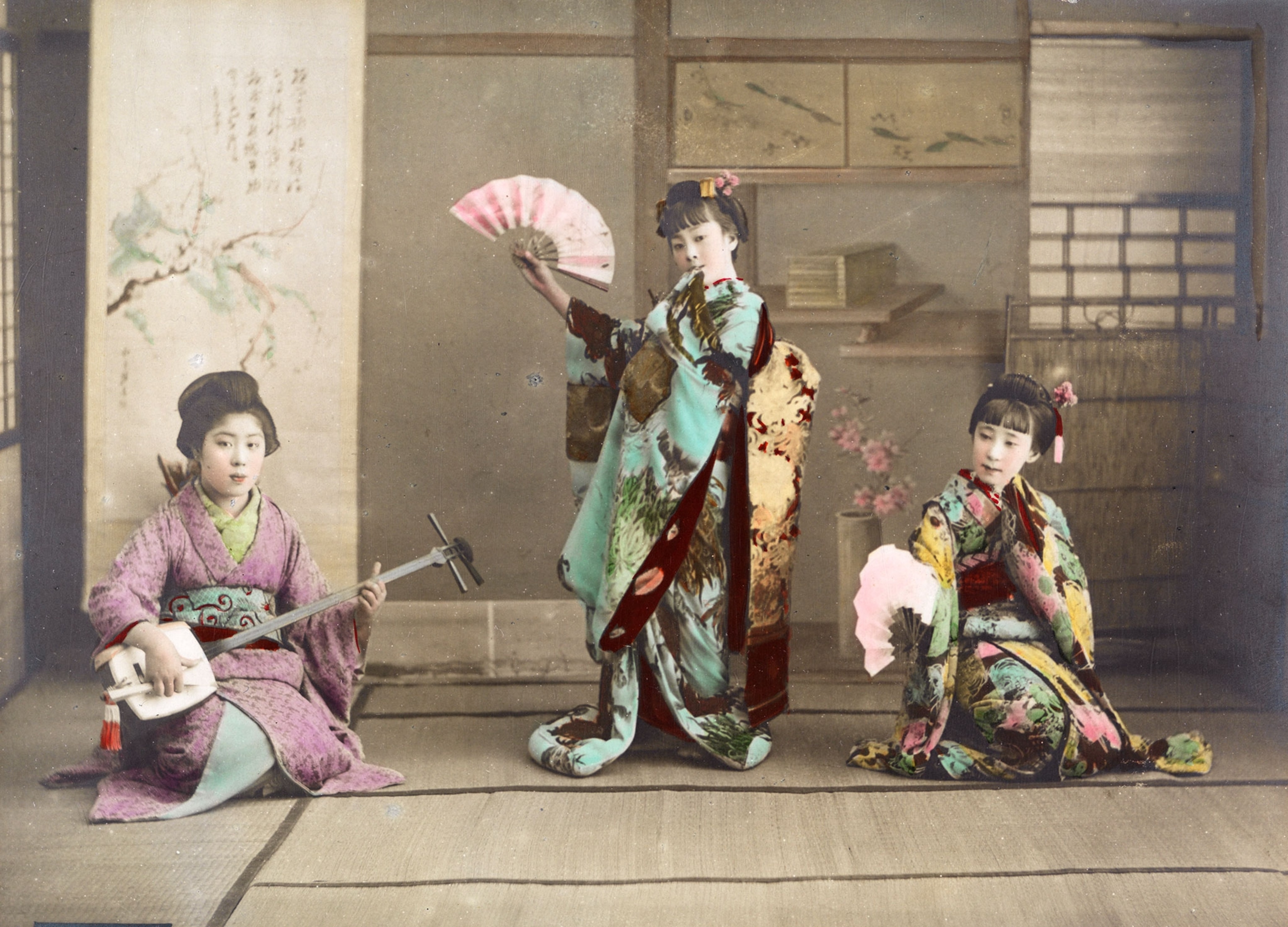 A musician, geisha, and dancing girls, maiko, pose for a portrait in Japan