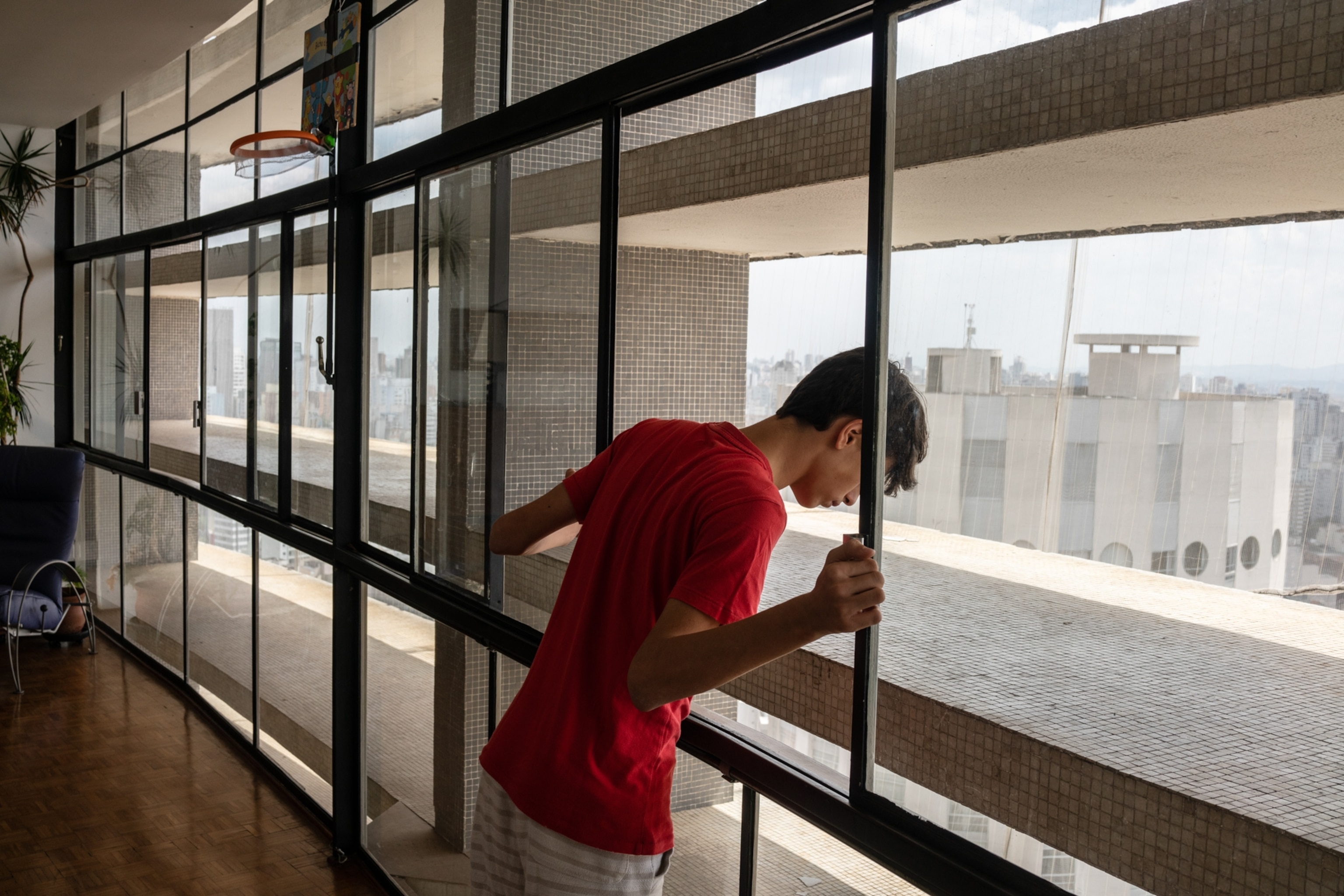 boy in a red shirt looking out of a window