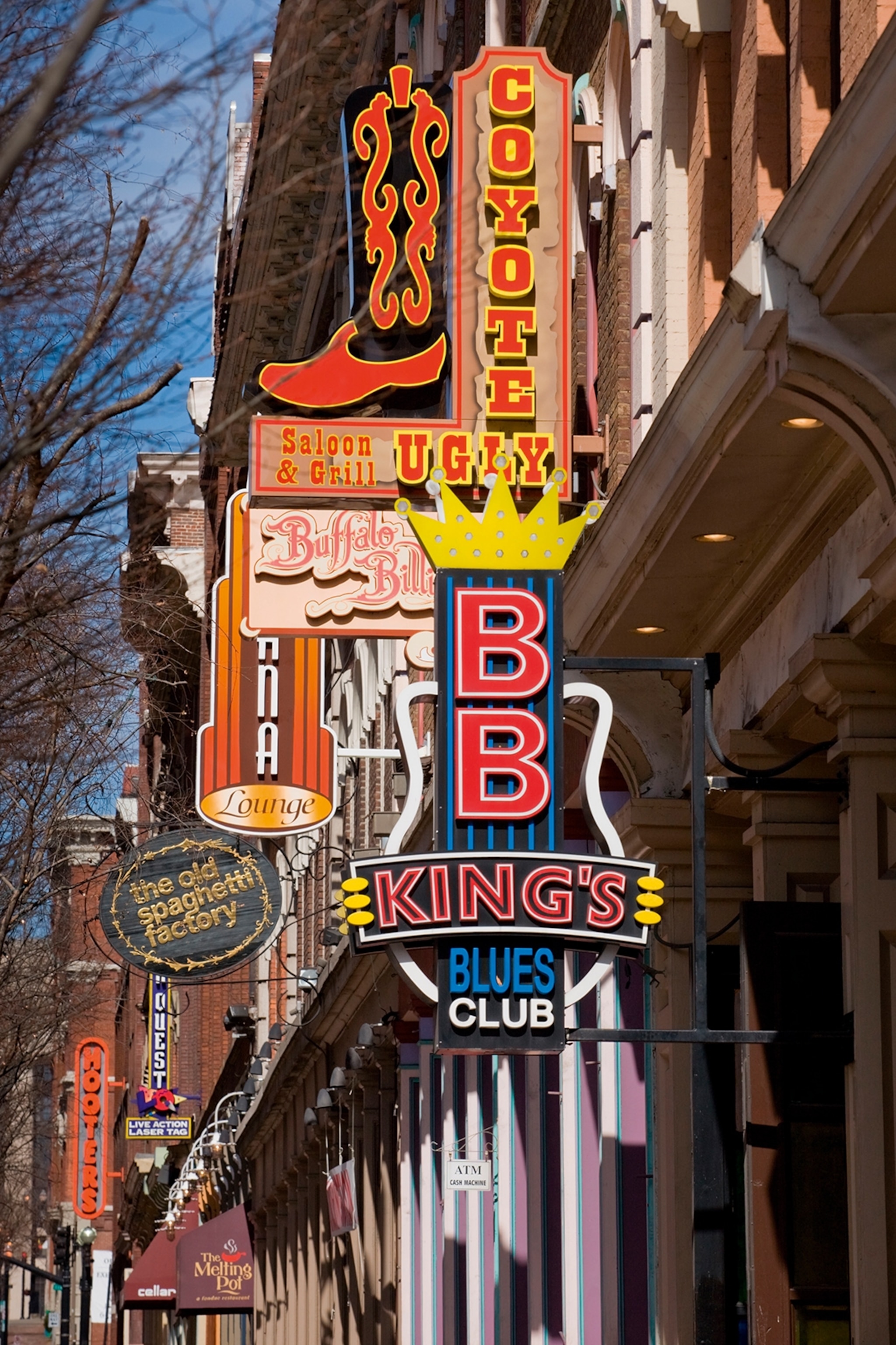 A close-up of staggered neon signs inviting to country- and blues-themed music venues.