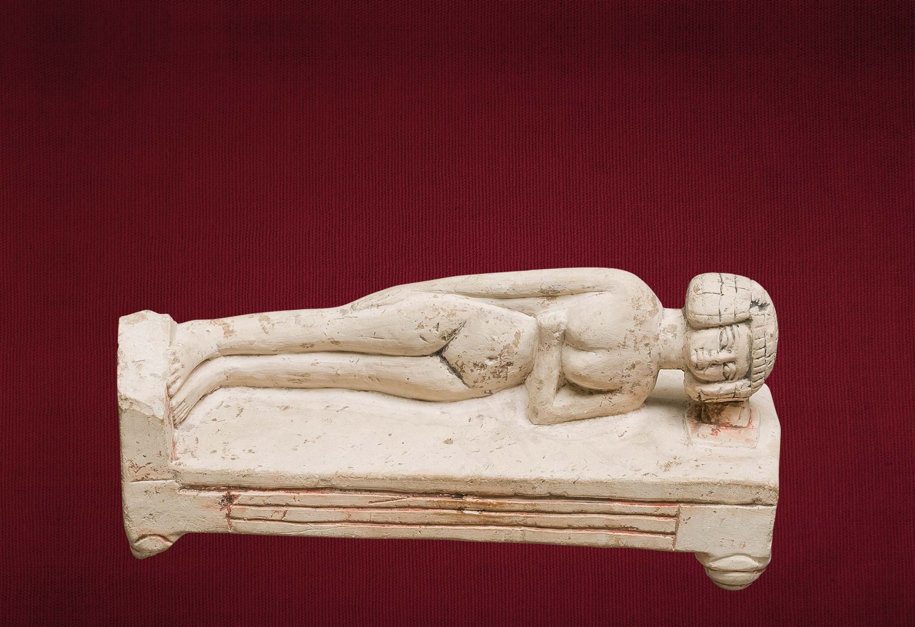 A headrest supports a woman’s head as she sleeps in an 18th dynasty limestone statuette.
