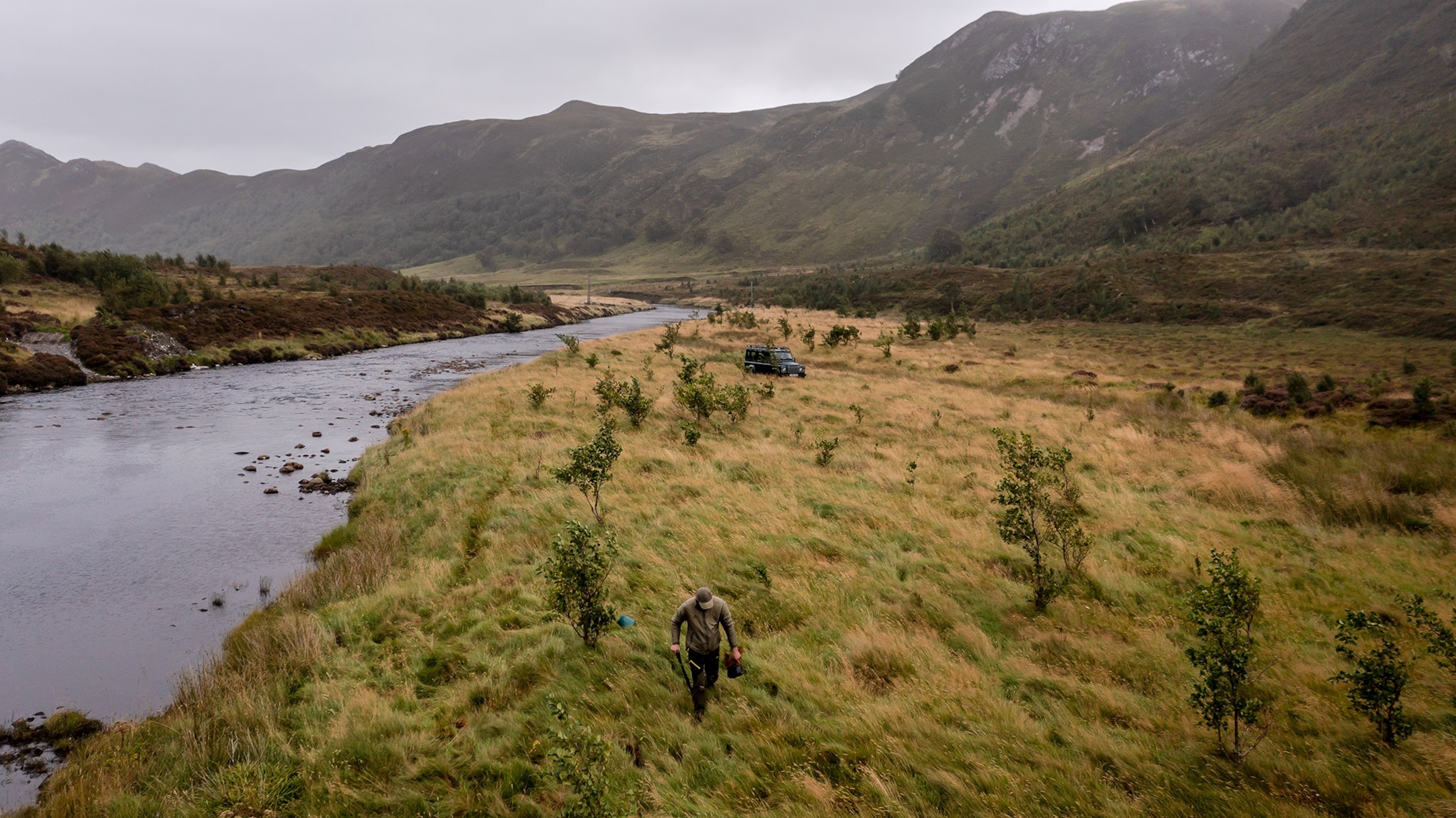 A ranger plants trees in Glen Mor on the banks of the river Abhainn a' Ghlinne Mhoir