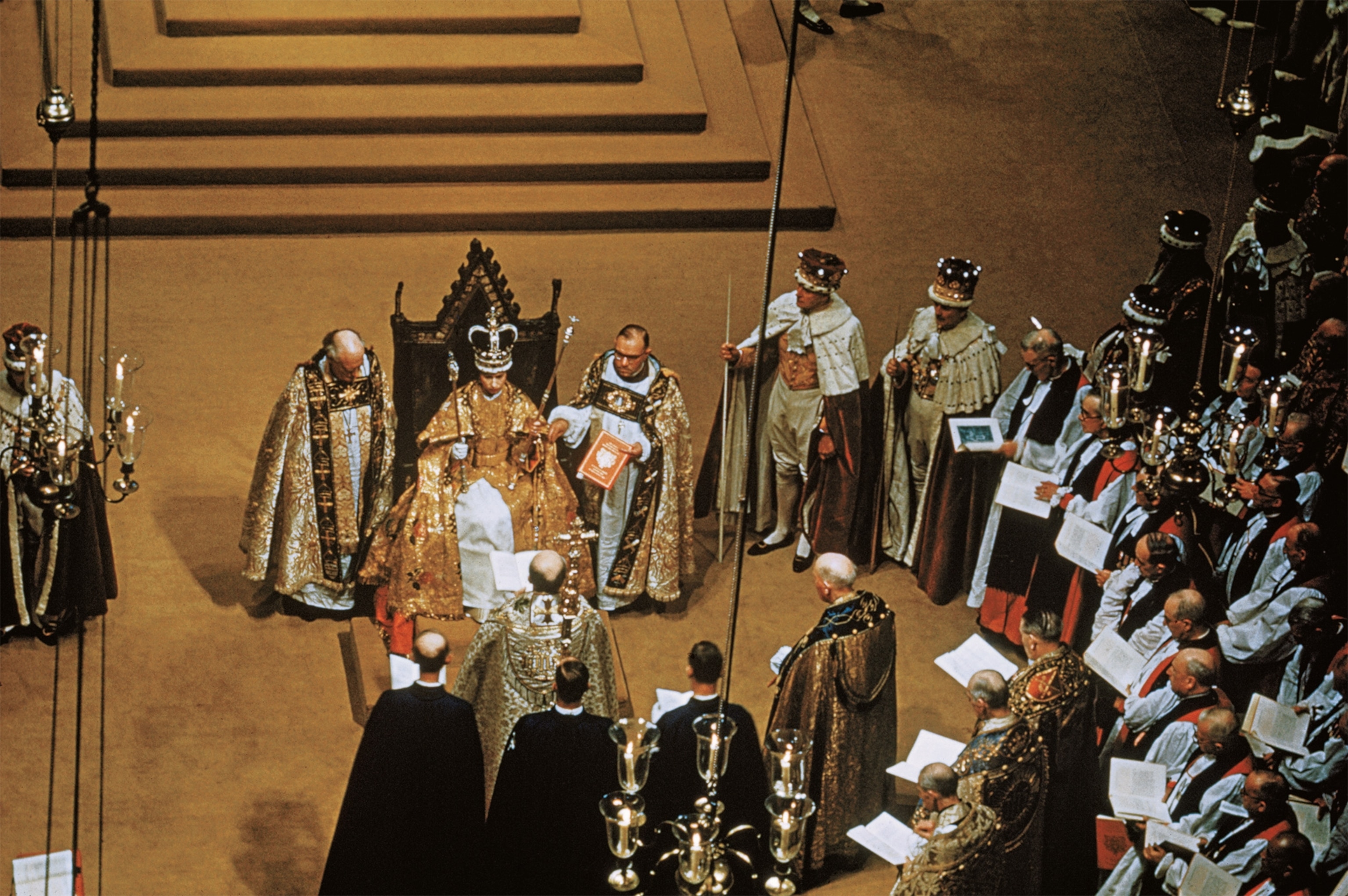 Elizabeth's 1953 coronation is pictured with the queen on a throne holding two scepters