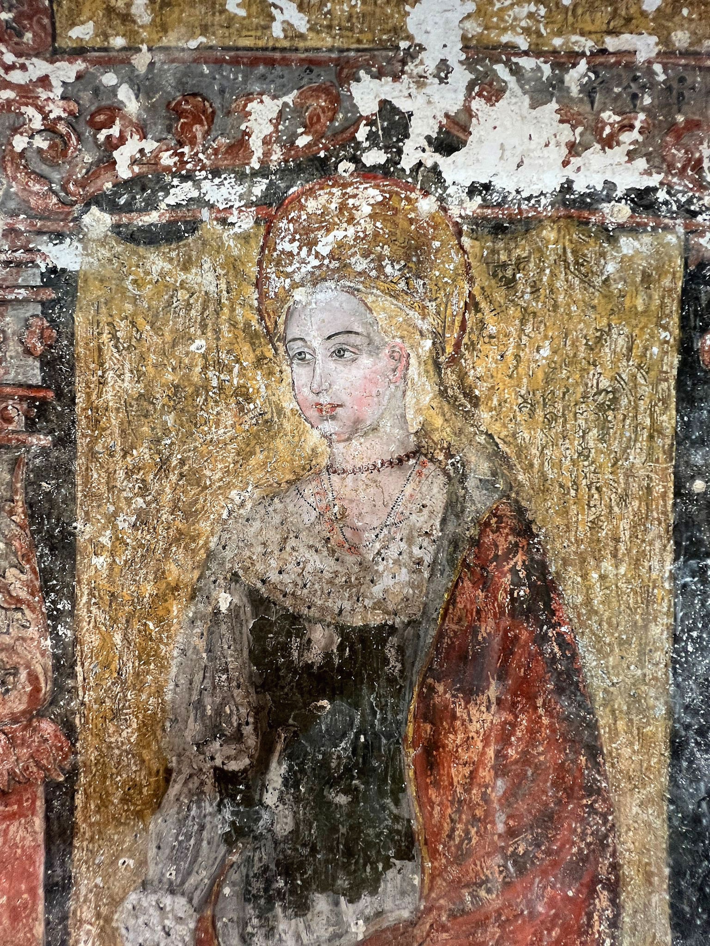 A worn fresco of a woman wearing a head piece
