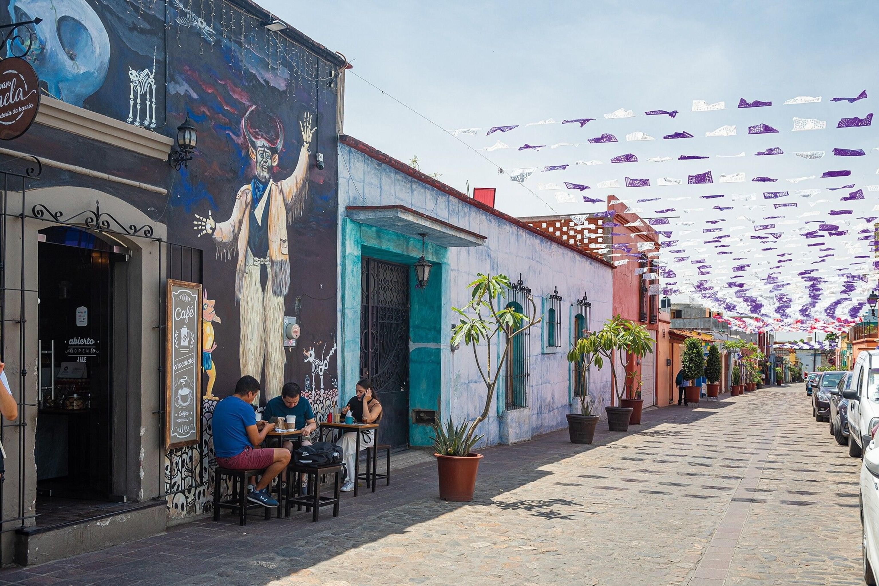 Locals enjoying a coffee break in Jalatlaco, one of the most colourful and popular barrios for street art. A lot of private houses, as well as shops and restaurants, have their walls painted with traditional scenes from folklore.