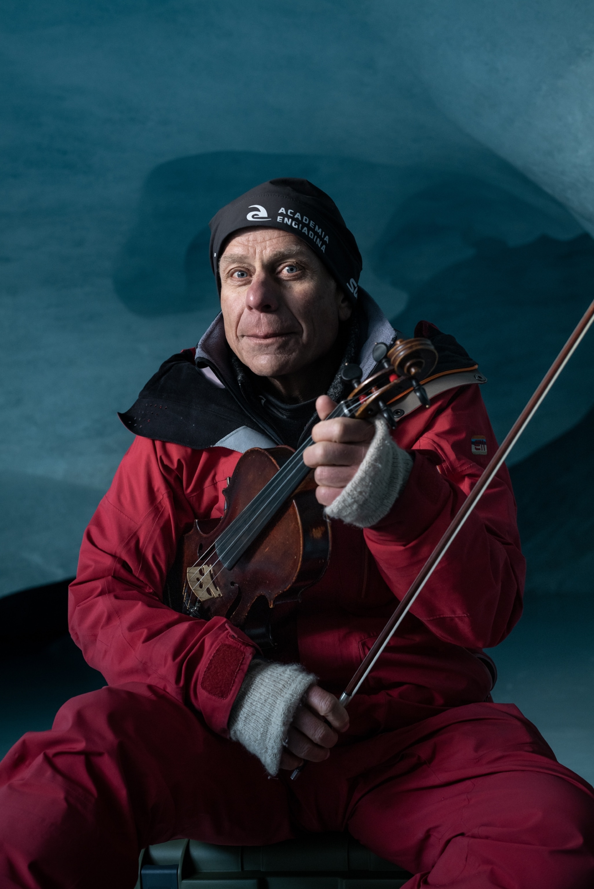 Picture of a man in read snow-suit posing with violin.
