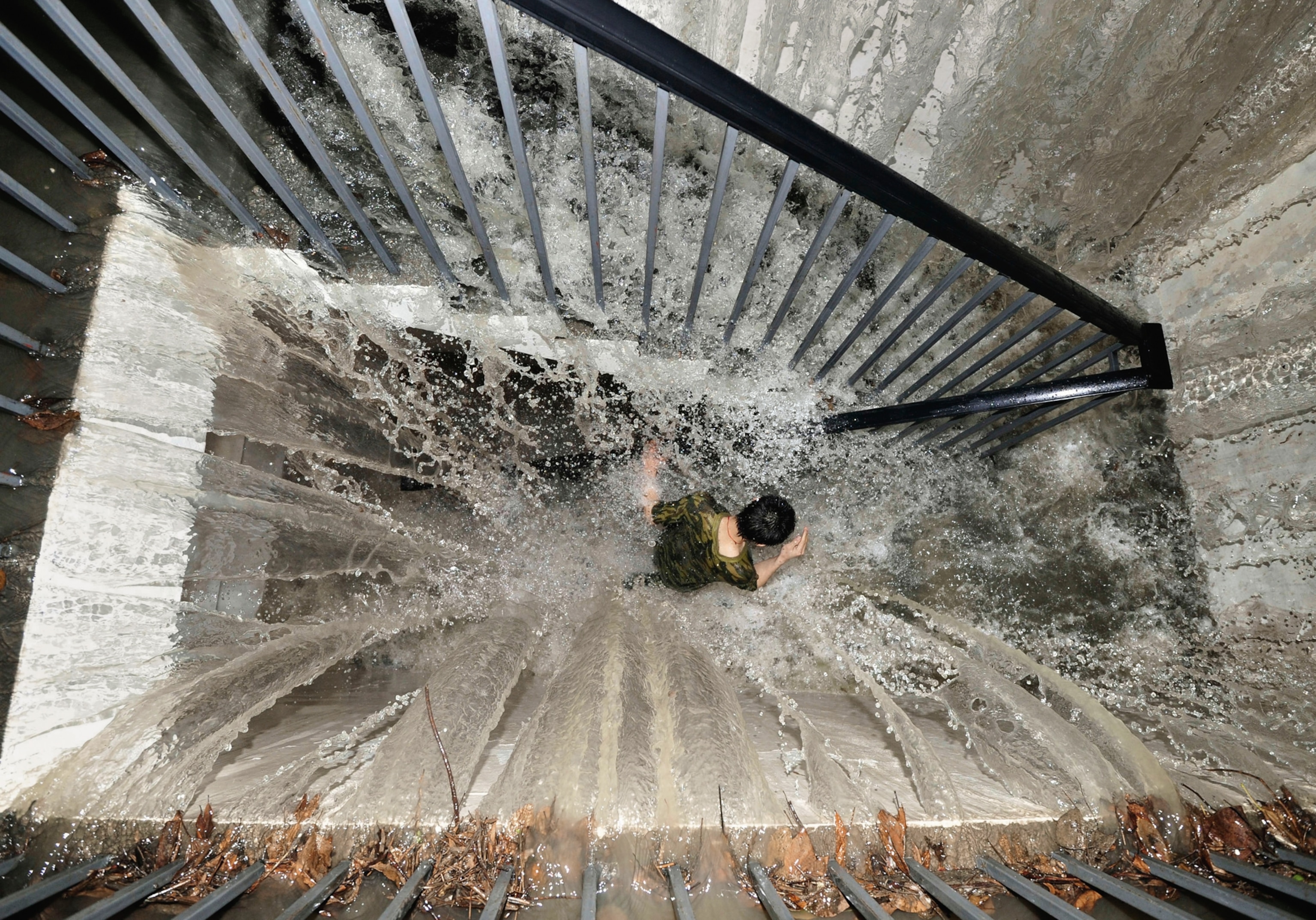 rainwater cascading down on a Chengdu resident rushing up a flight of stairs