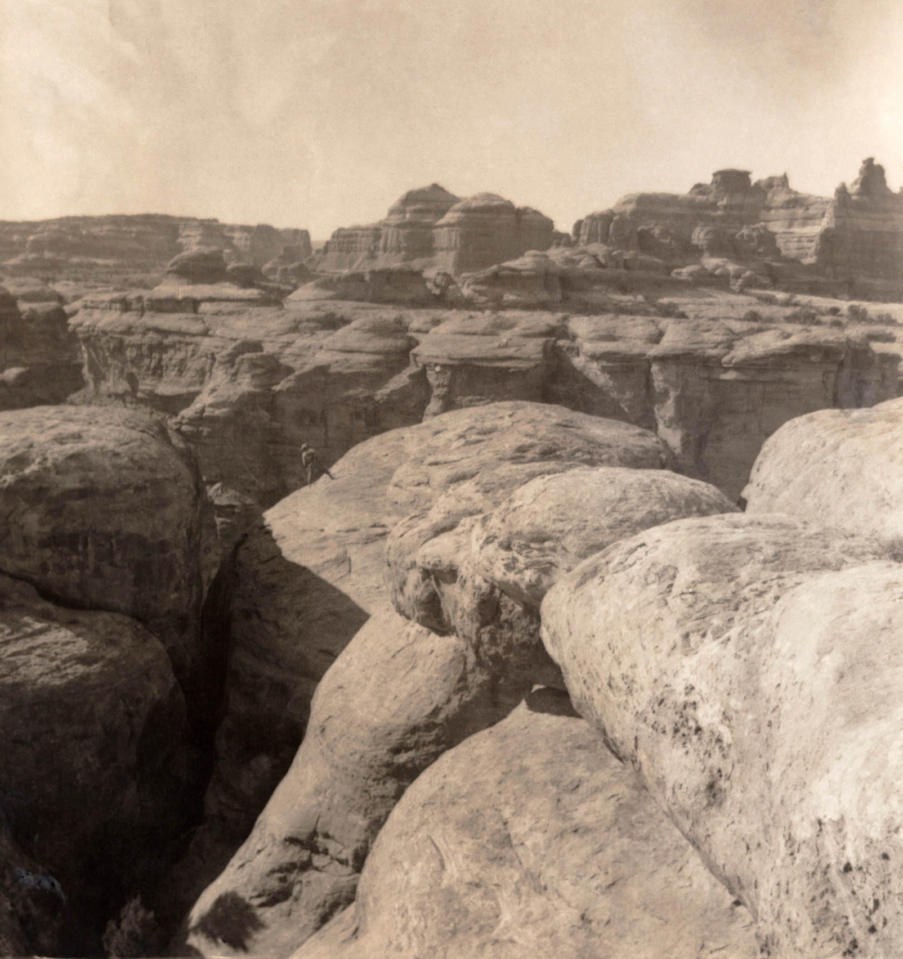 Sepia image of person standing in a large canyon expanse