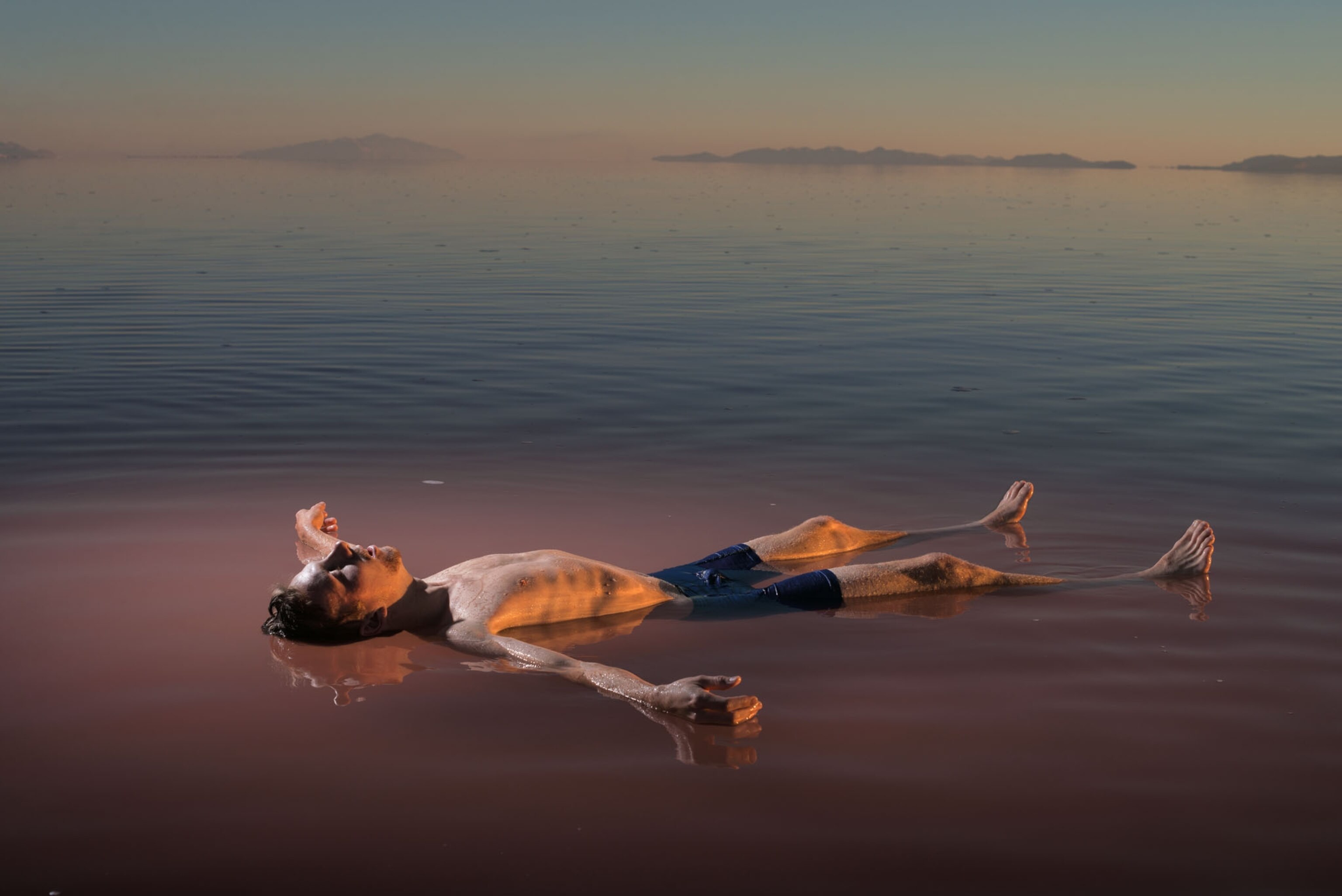 a young man floating in a lake during sunset