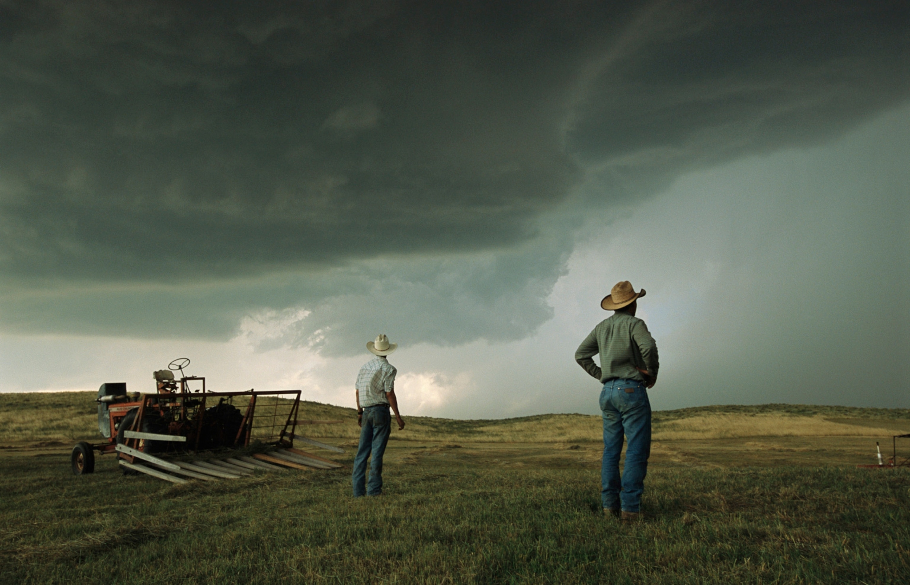 A thunderstorm halts haying as two farmers watch the sky