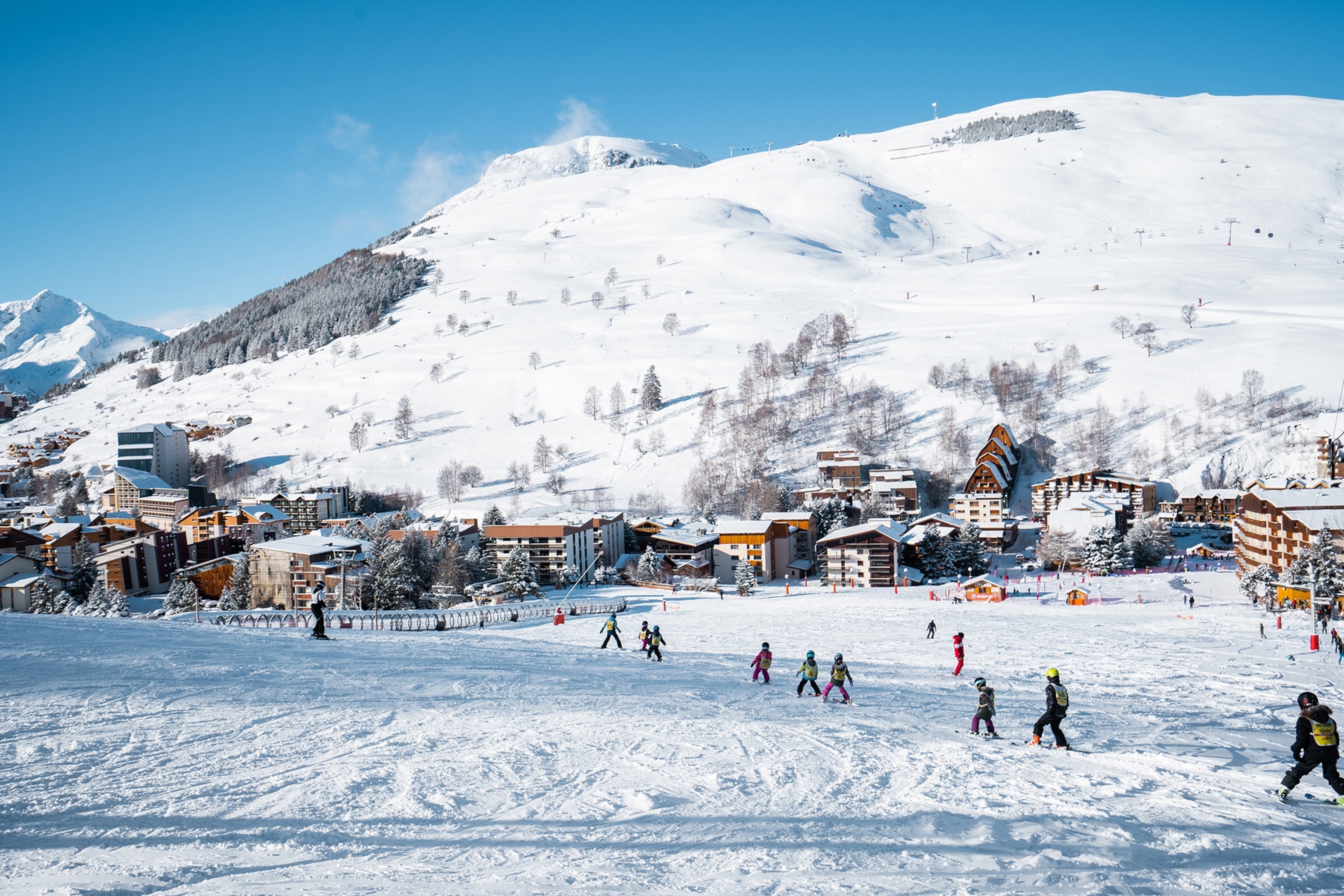 A vista of children learning to ski on a mountain at Les Deux Alpes in the French Alps, France.