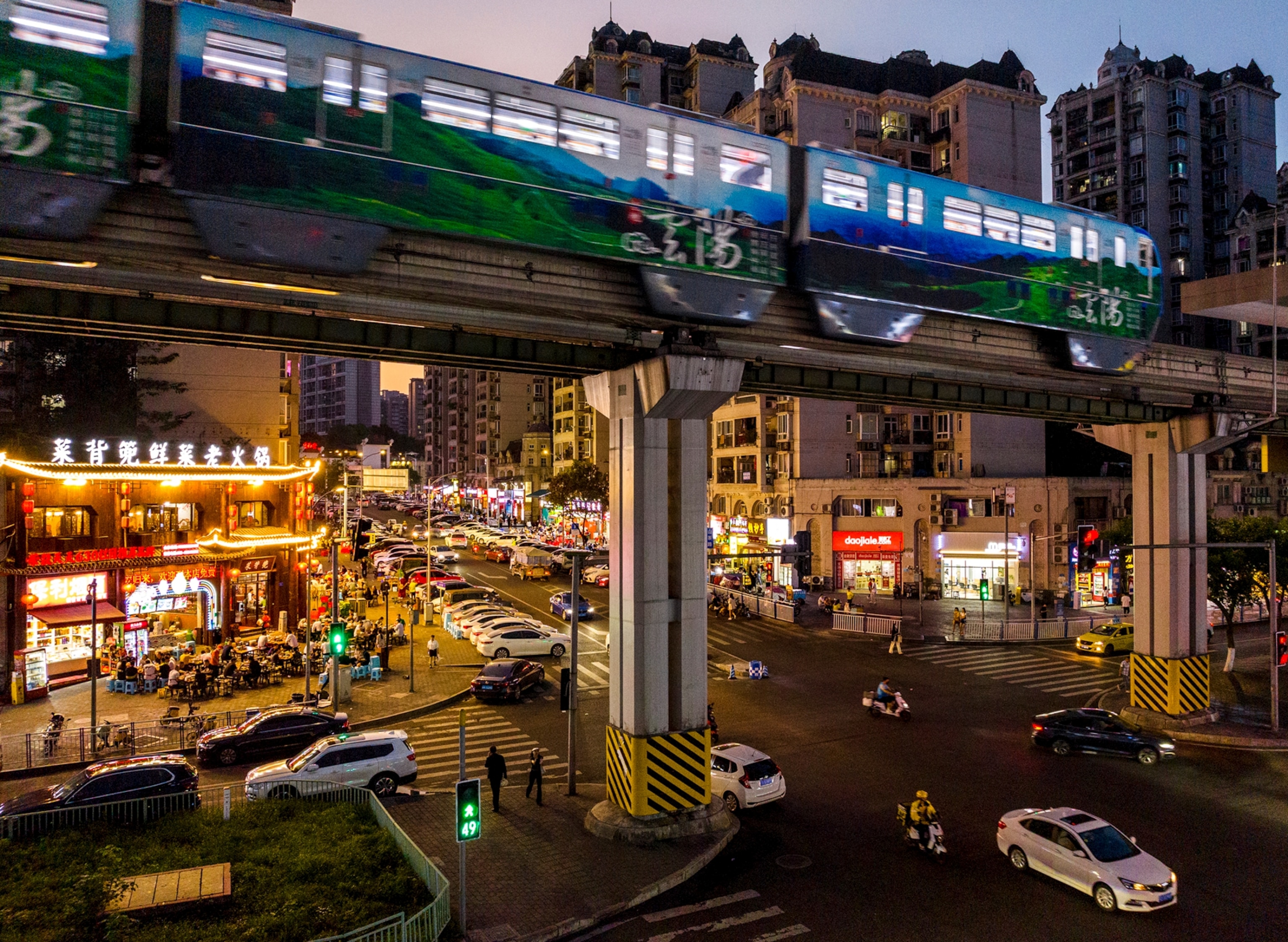 Picture of a metropolitan area with a train going overhead and a busy street below.