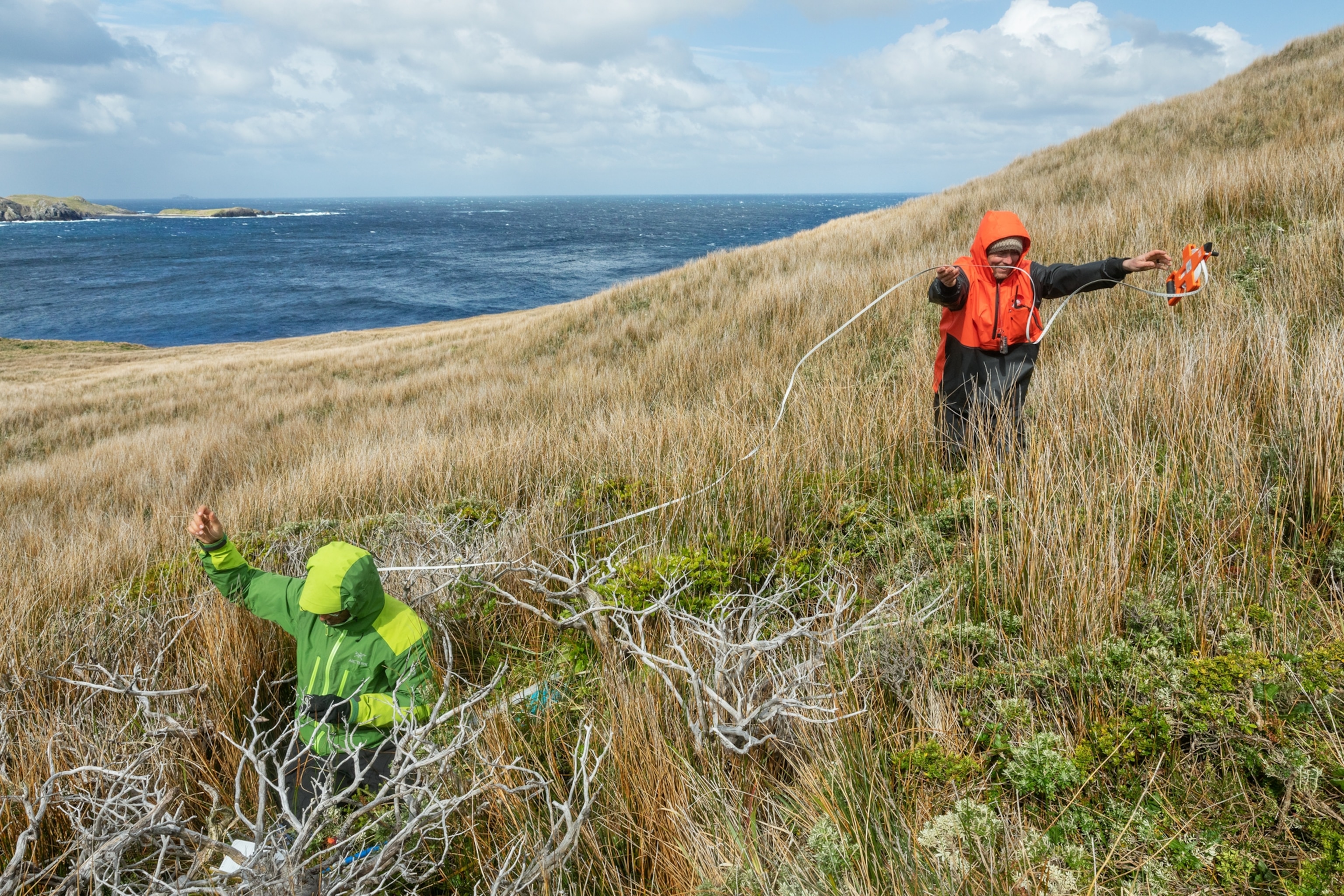 Picture of man in red jacket and man in green jacket using measurement tape.