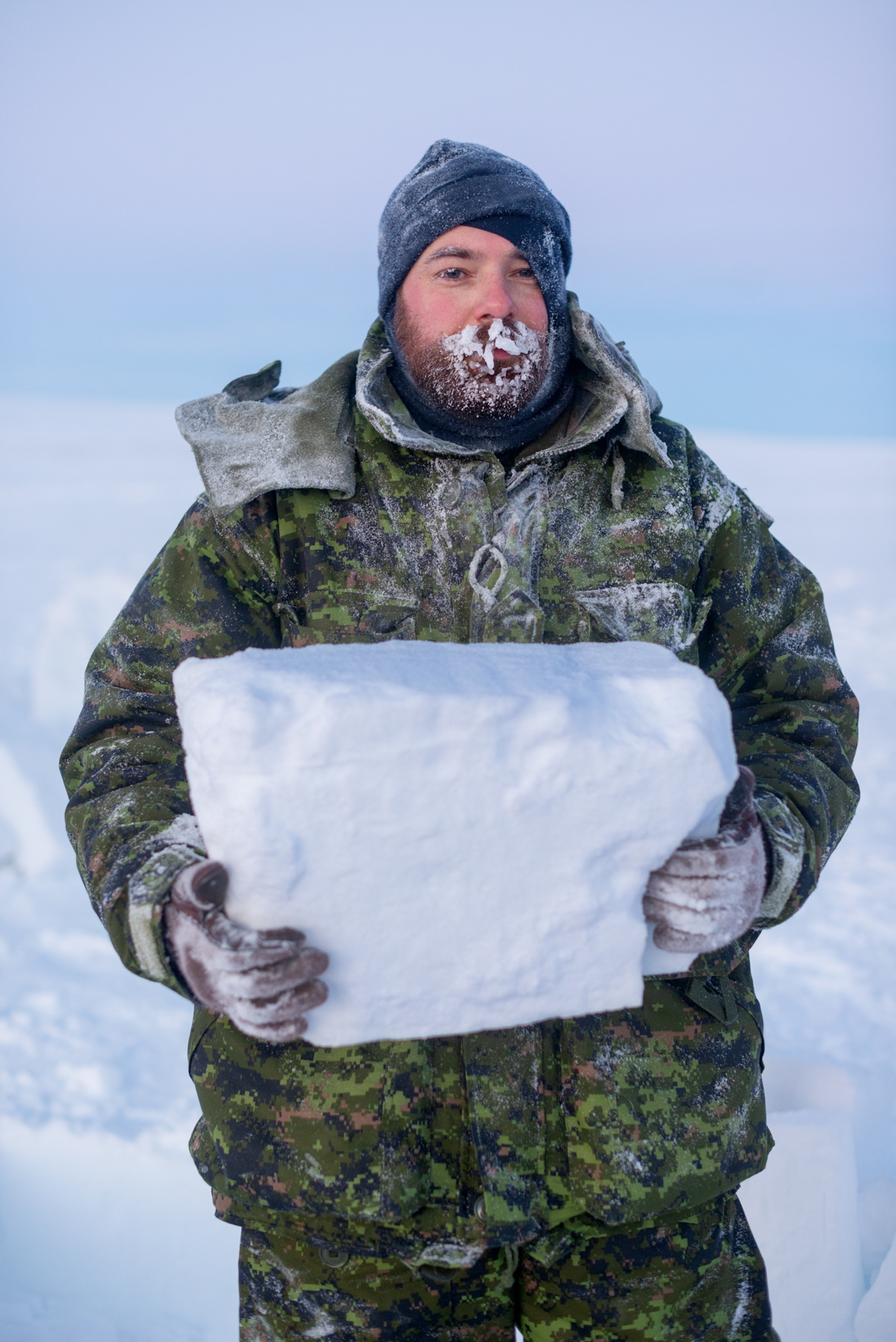 a man with ice-covered beard holding a block of ice.