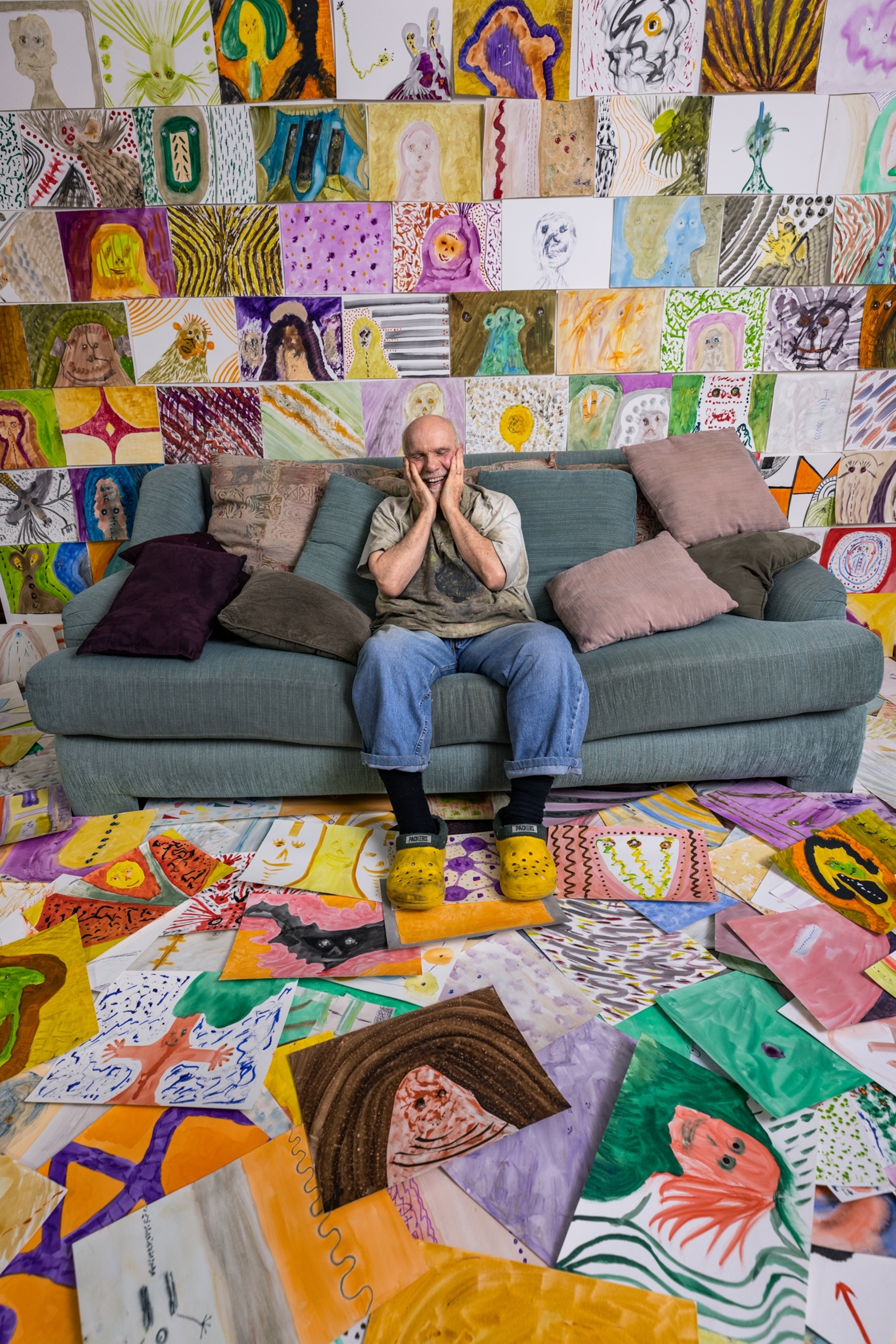 Picture of a man lifting on sofa and looking at pictures on floor.
