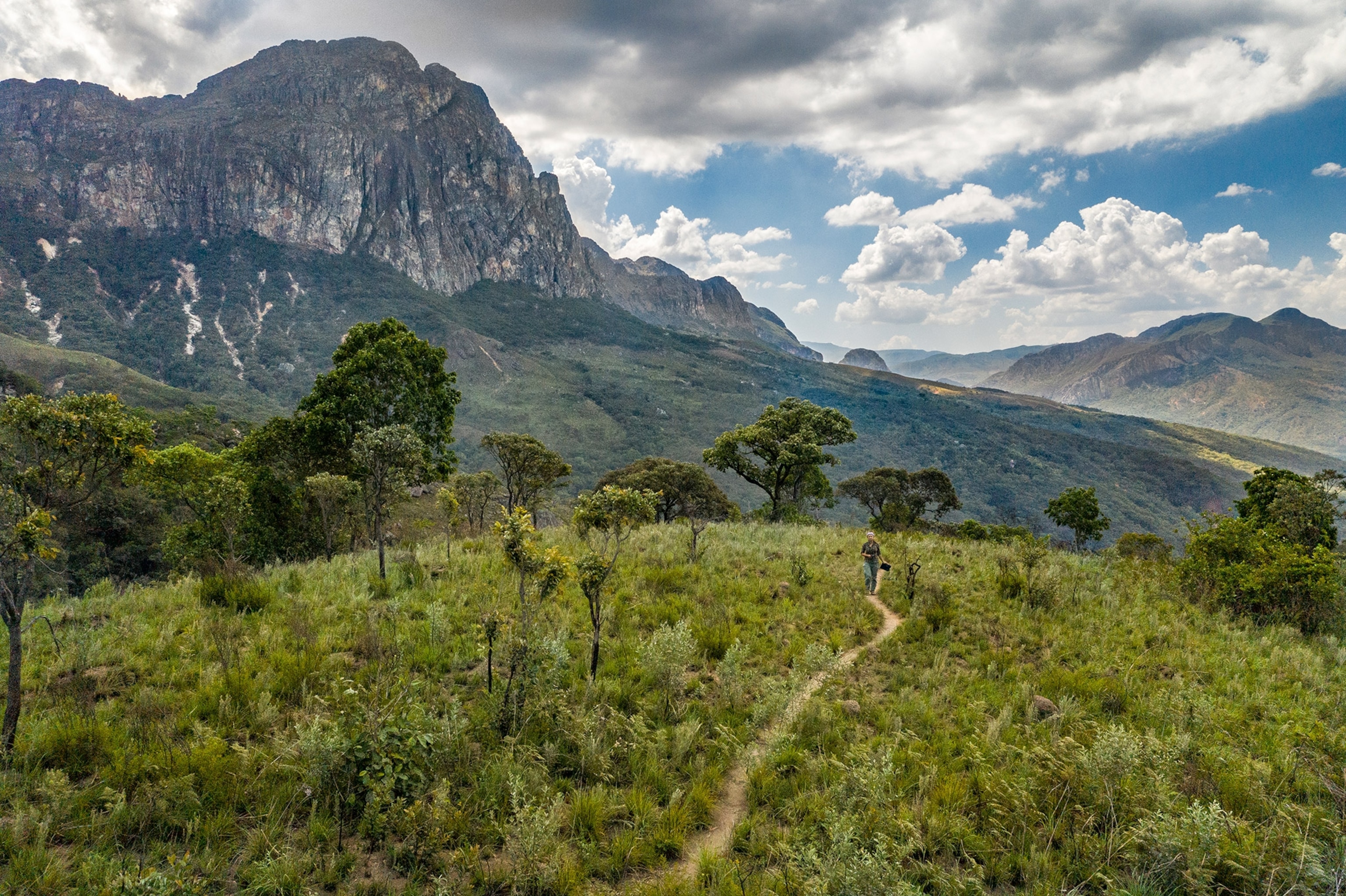A woman walks along a mountain trail