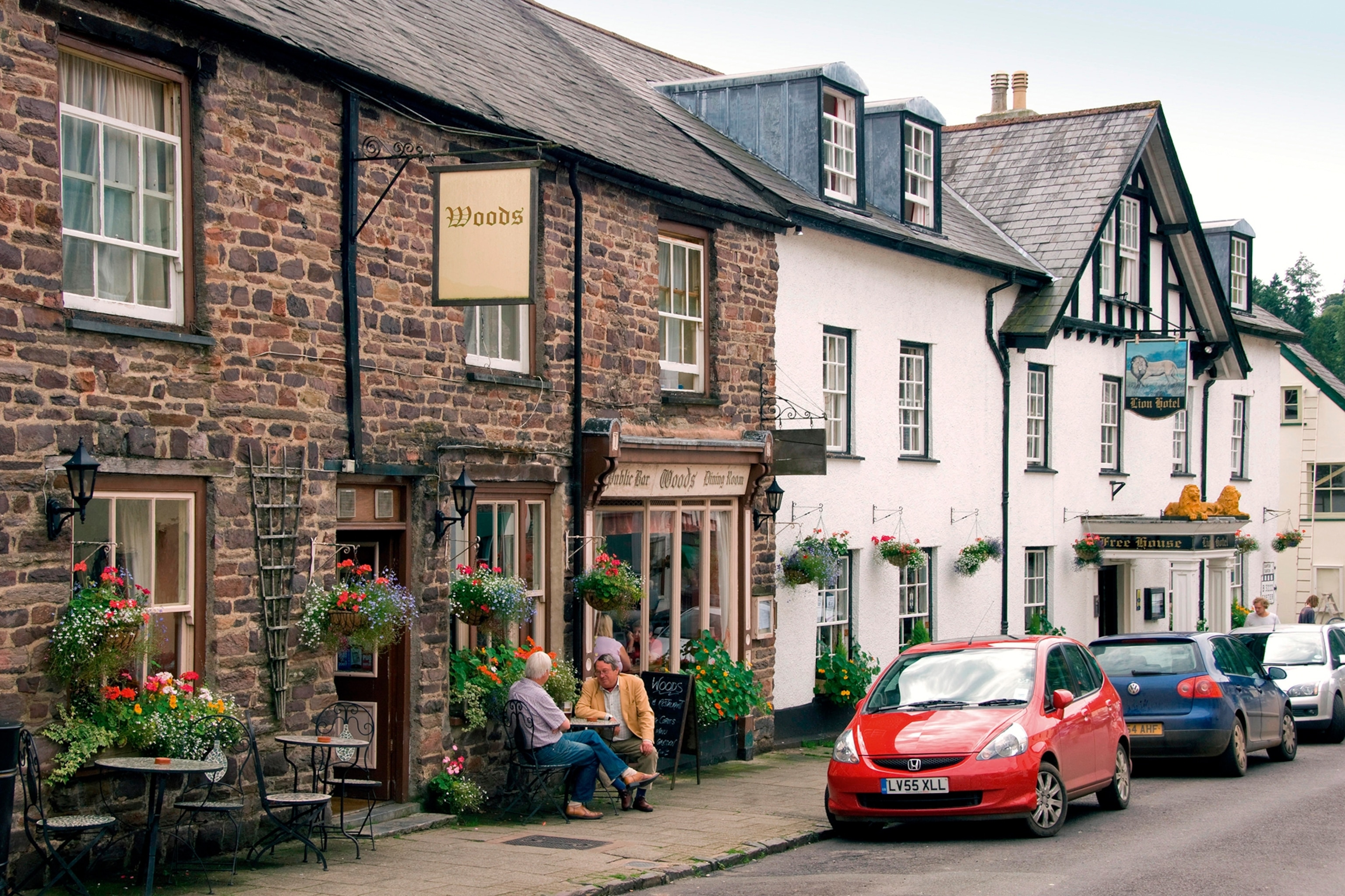 A traditional, brick pub with flower pots at the entrance and located on a quiet street.