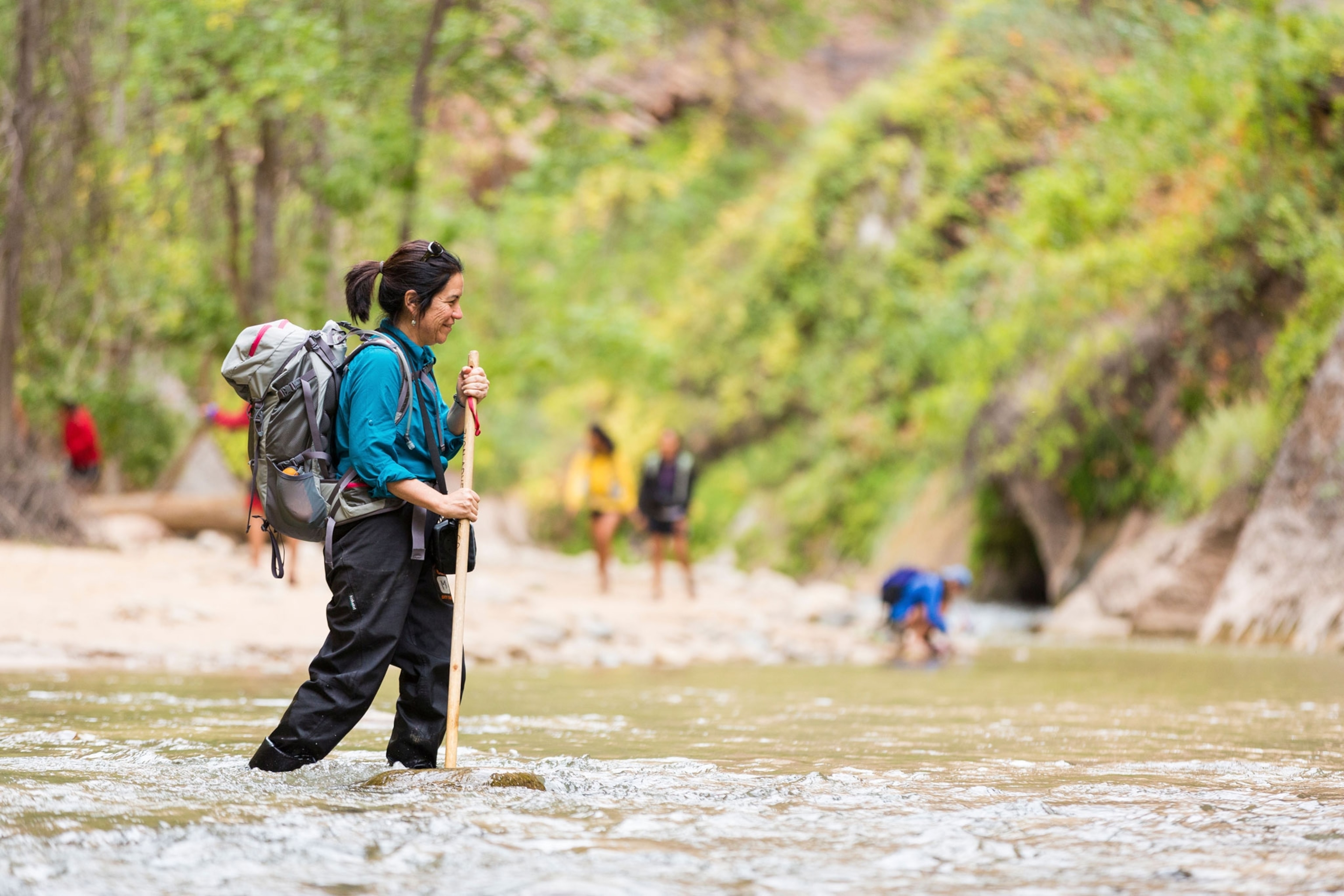 Woman crossing a Virgin River at The Narrows in Zion National Park, Utah