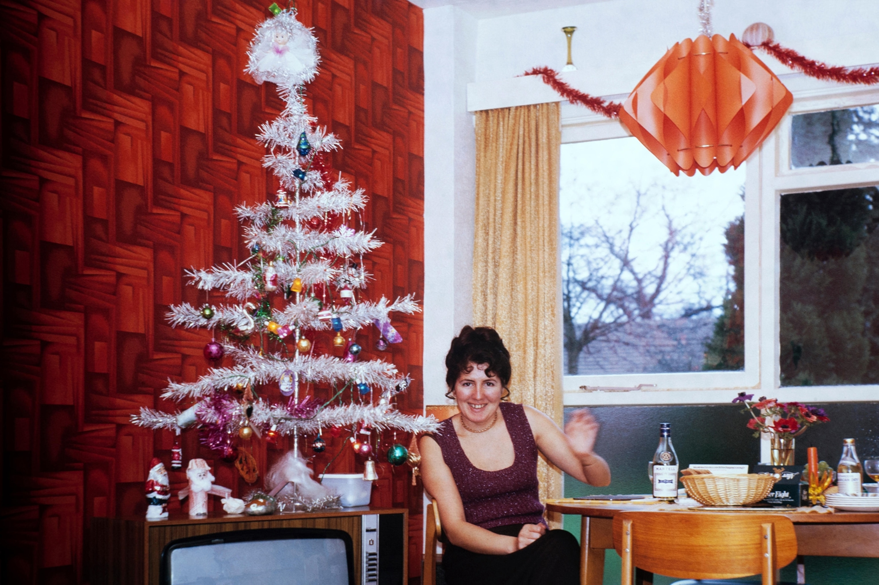 A woman with a white tree and a white wall in a room.