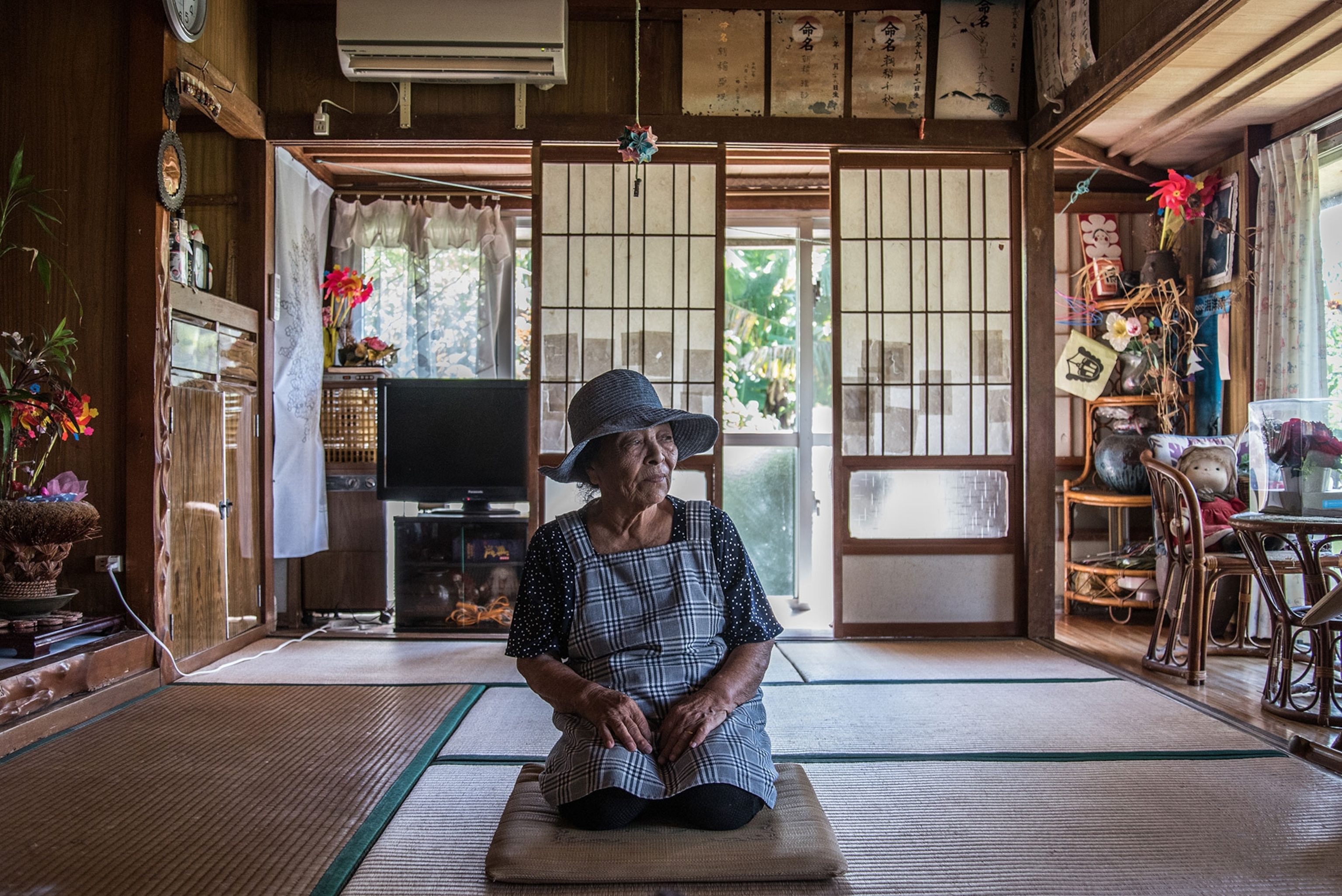An 88 year old woman kneels in the center of an open room.