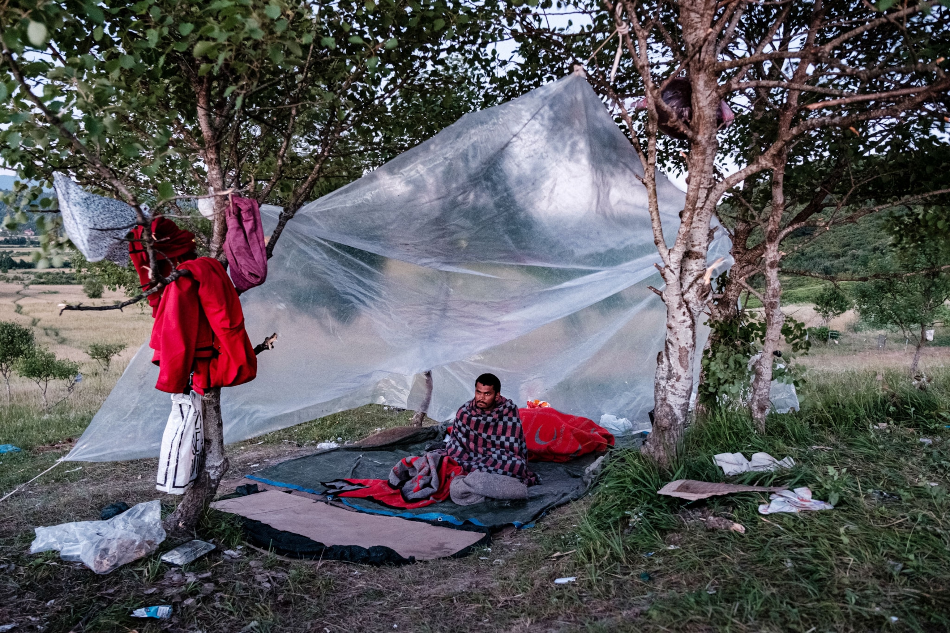a migrant sits in a makeshift shelter in Bosnia