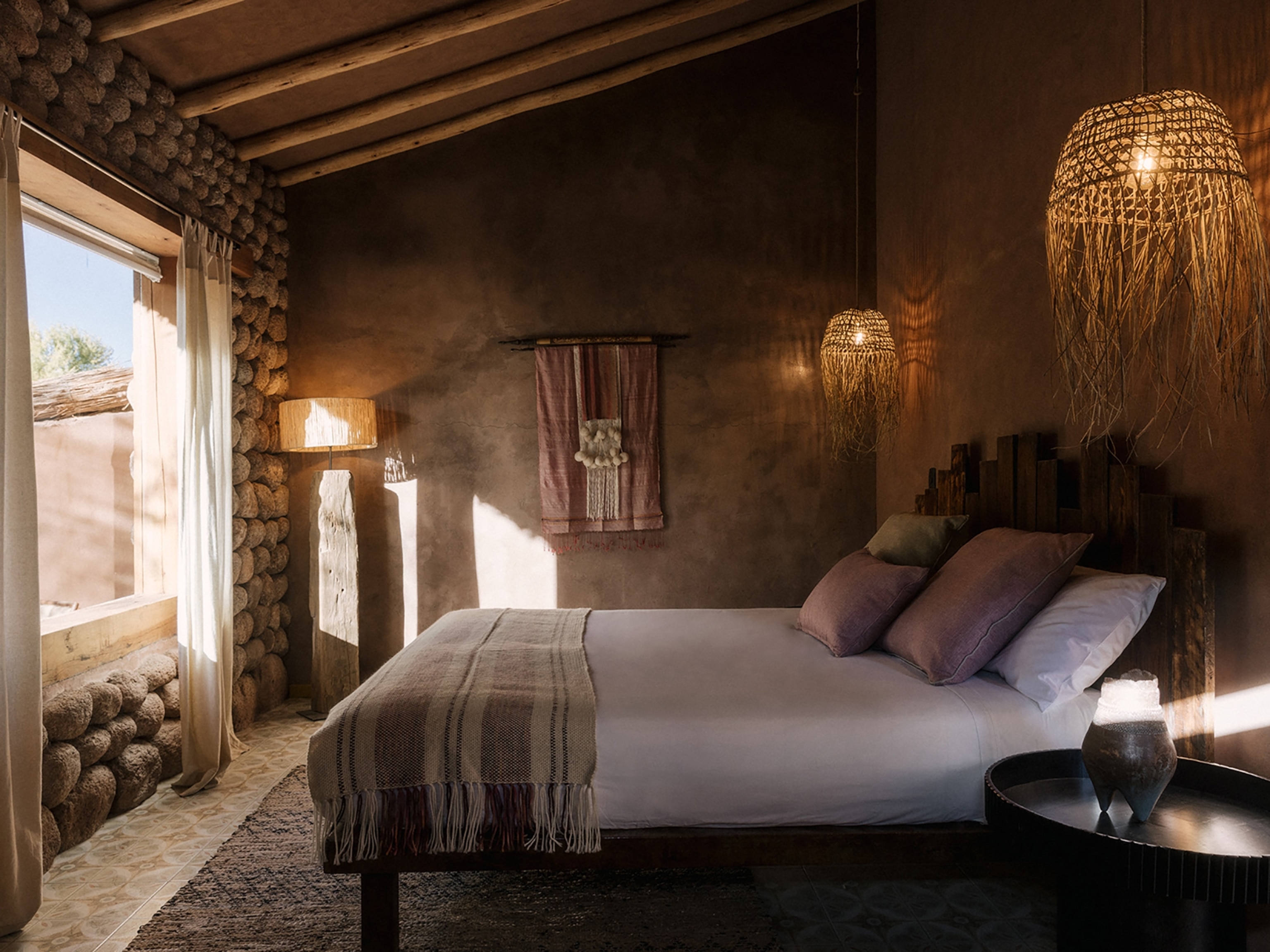A hotel room in earthy brown colors with light streaming through the window.