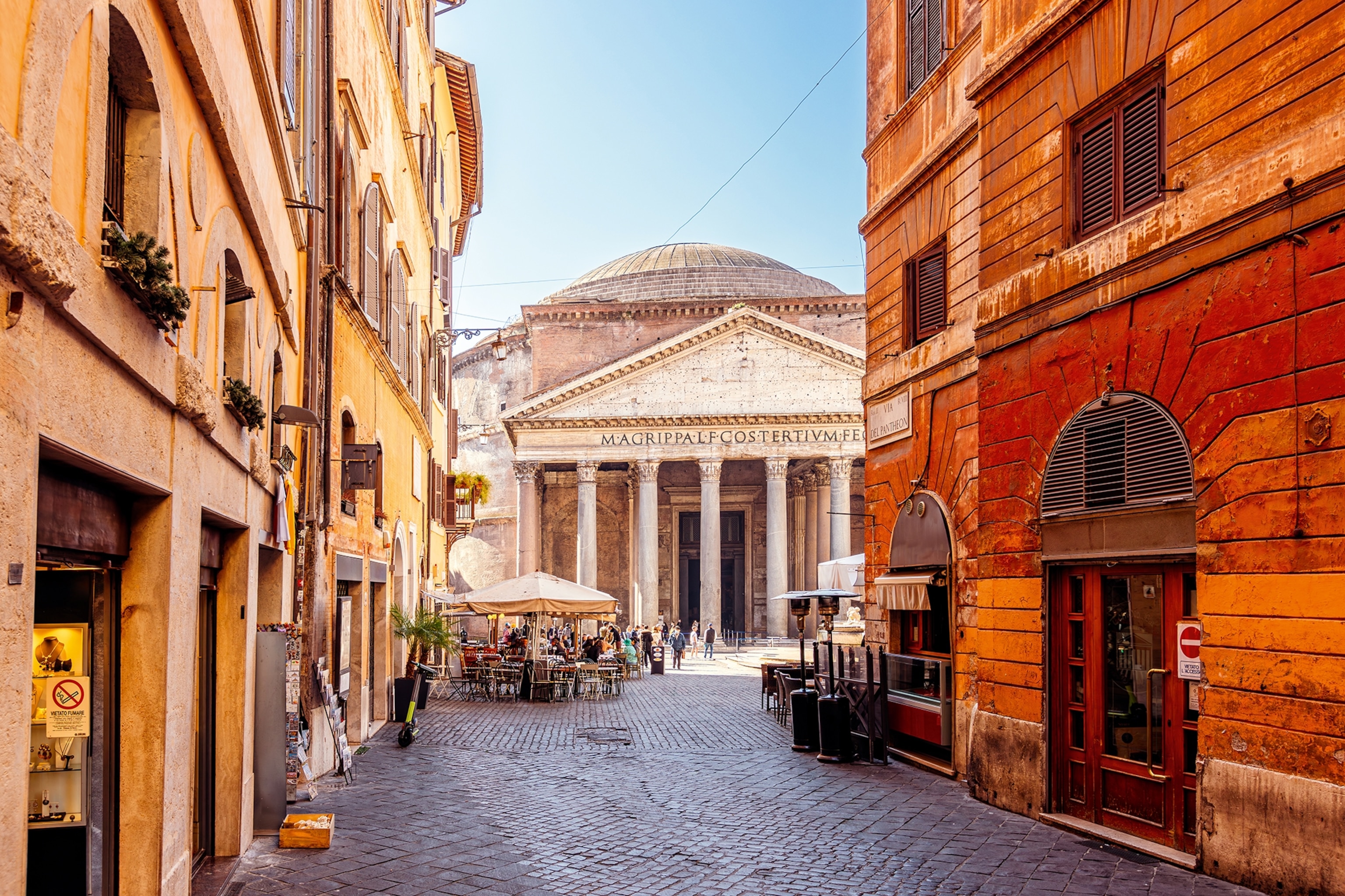 A traditional Italian marketplace between dense townhouses, an ancient Roman building in the center.