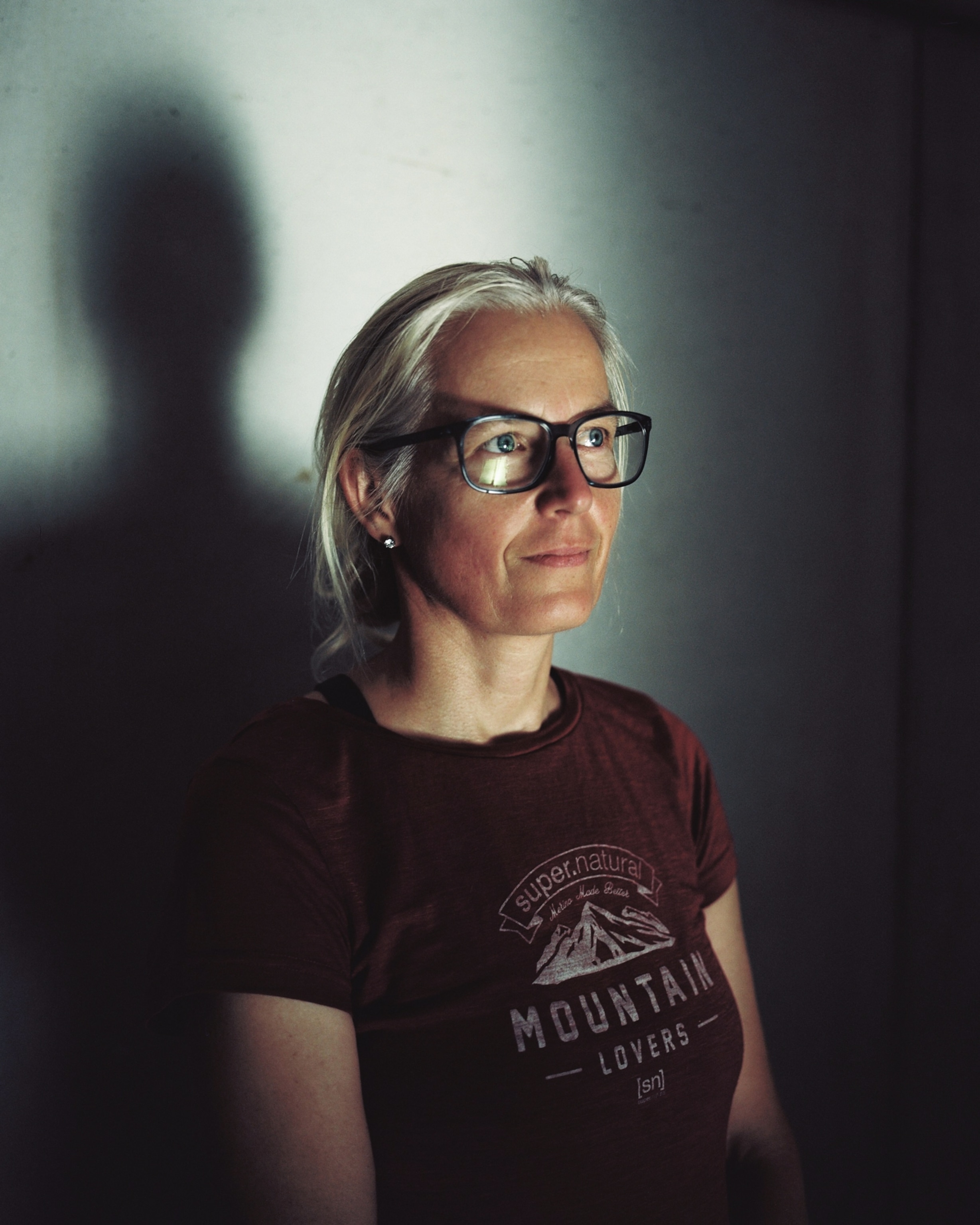 a portrait of a women with grey hair and square framed glasses