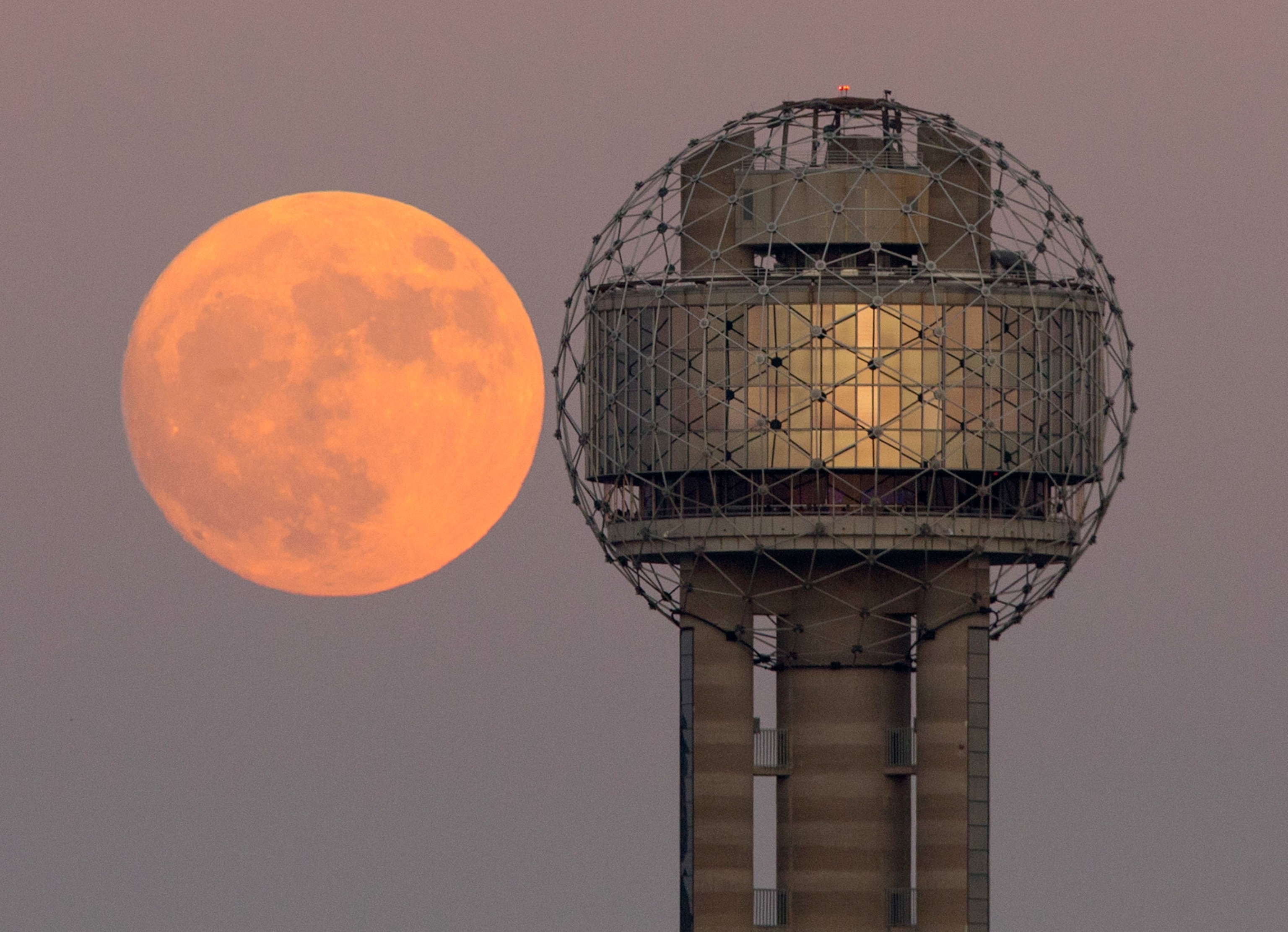 moon rises behind Reunion Tower in downtown Dallas