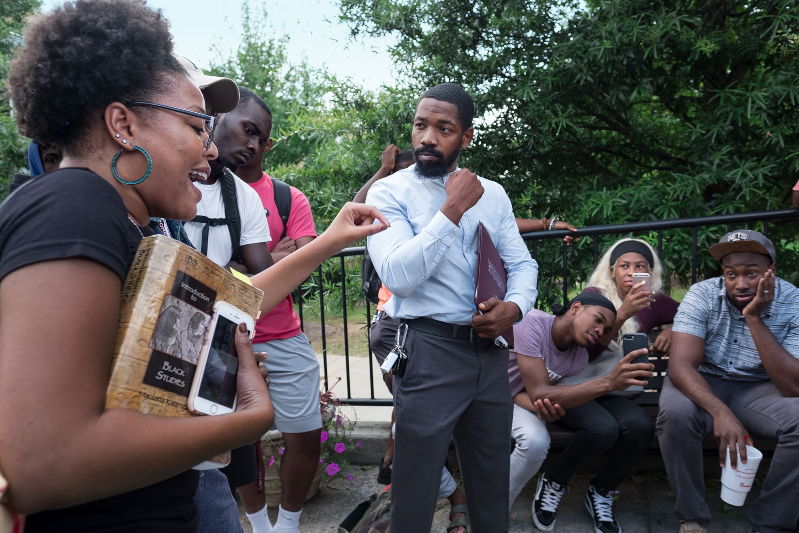 a black teacher speaking with multiple students outside