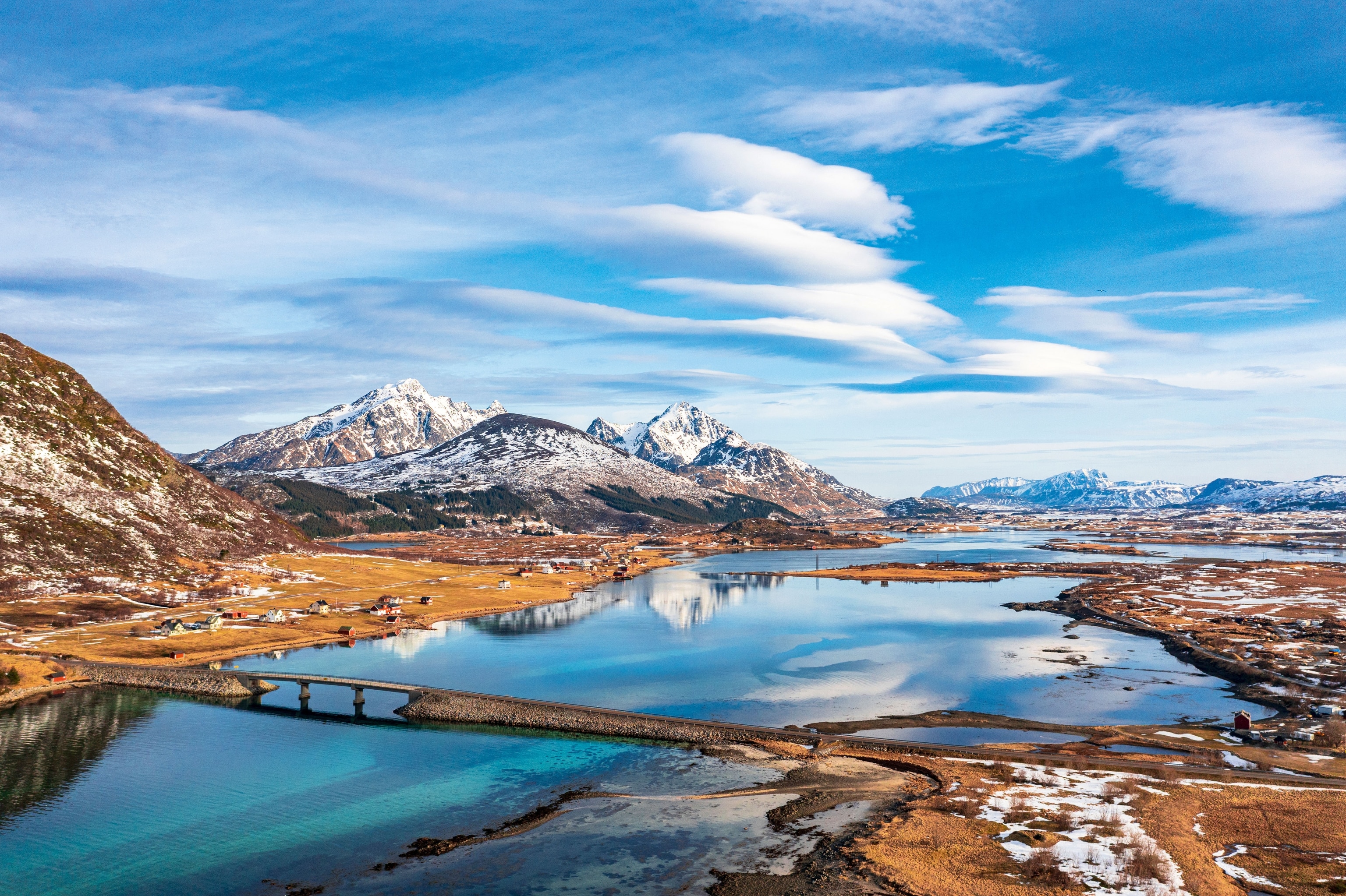 mountains reflected in the sea surrounded by snowed lands