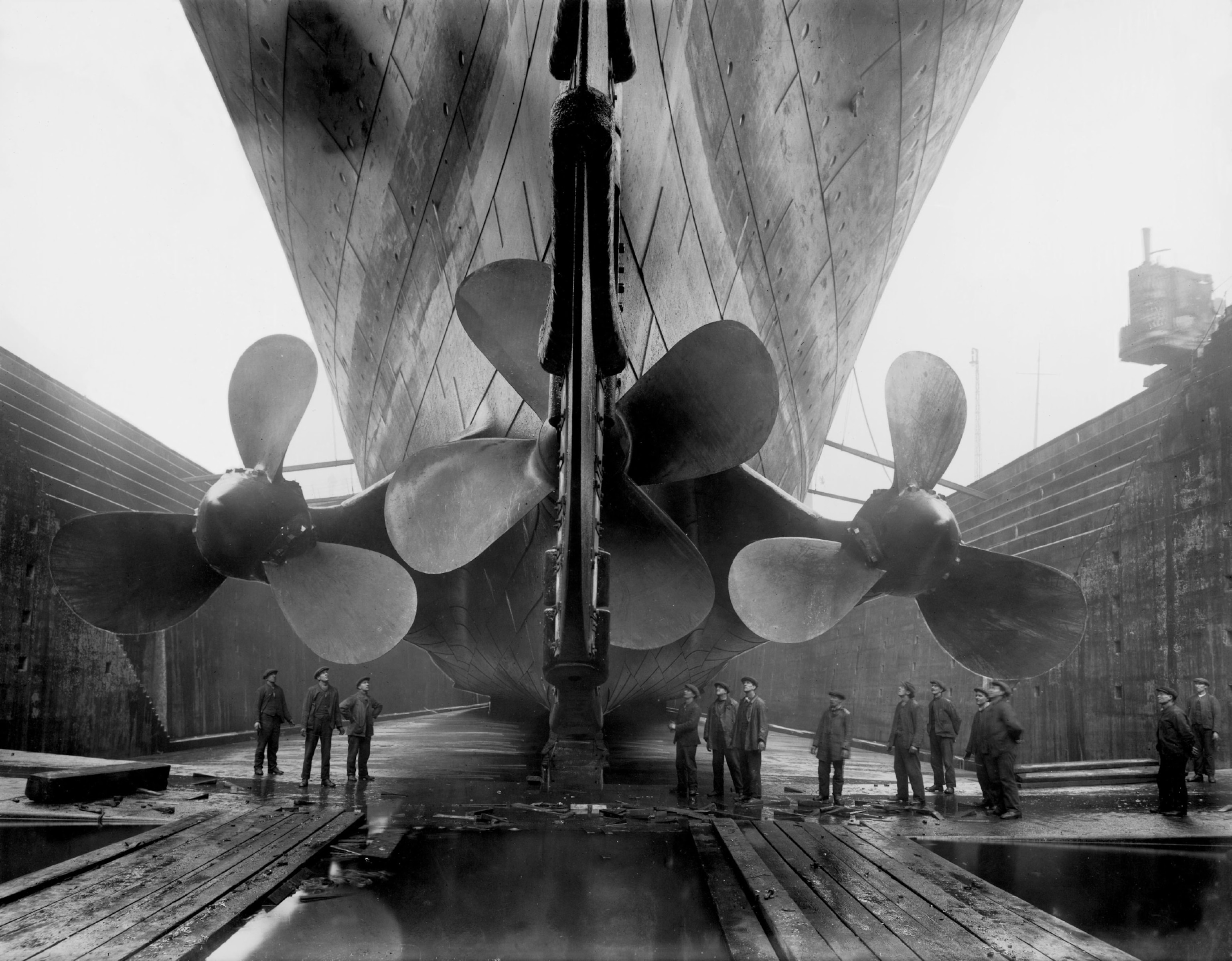 Several men stand beneath the giant propellers of the theTitanic