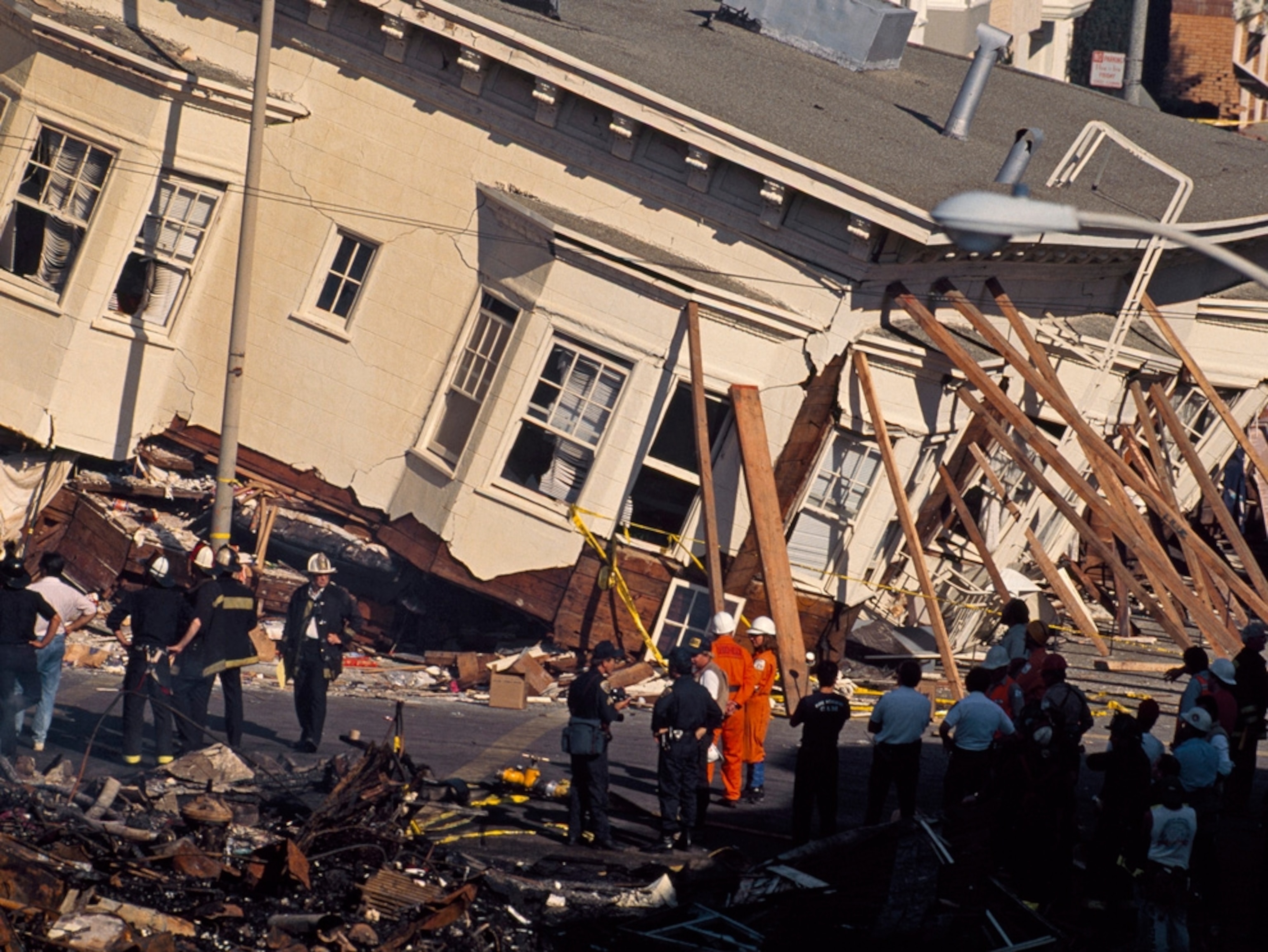 Pink row houses, tilted dangerously by an earthquake, and held up by wooden beams