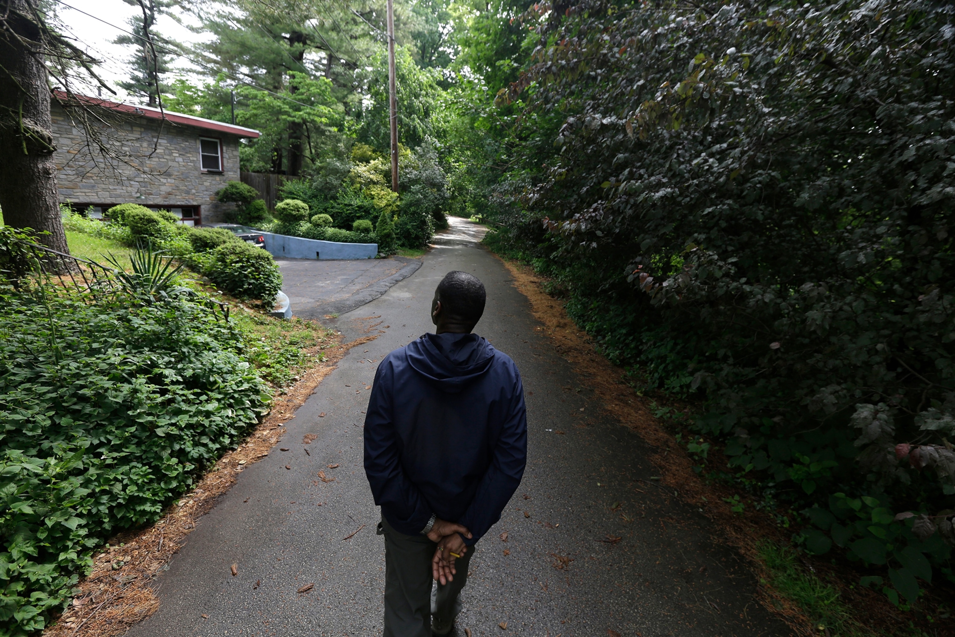 a man walking down a road surrounded by ivy and bush