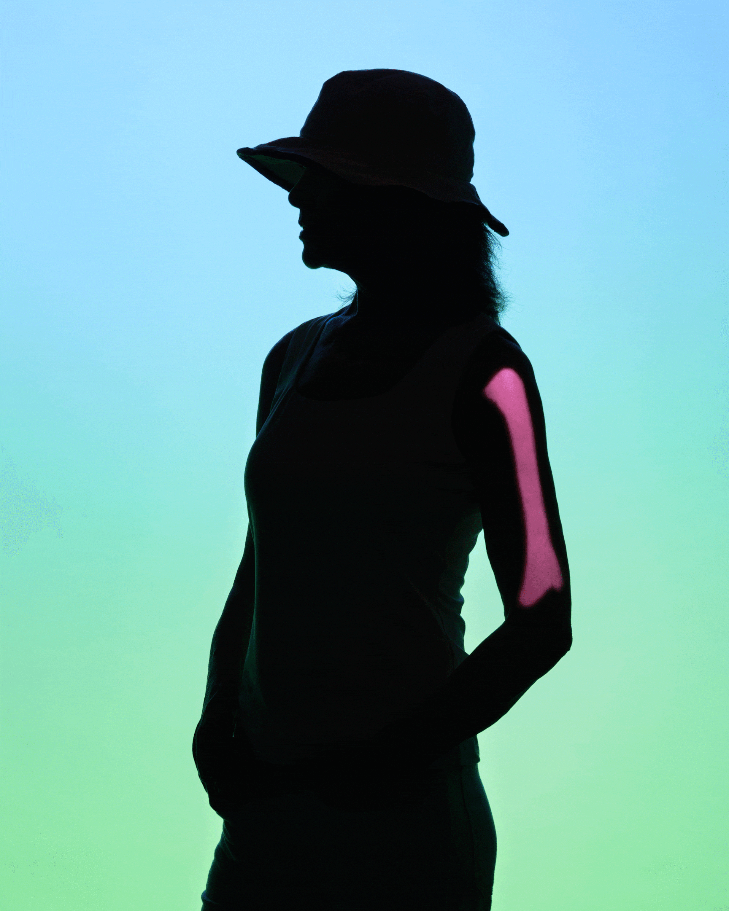A woman silhouetted against a background that fade from light blue to light green; projections of a heart, brain, and humerus bone cycle every second, appearing on the silhouetted woman's body
