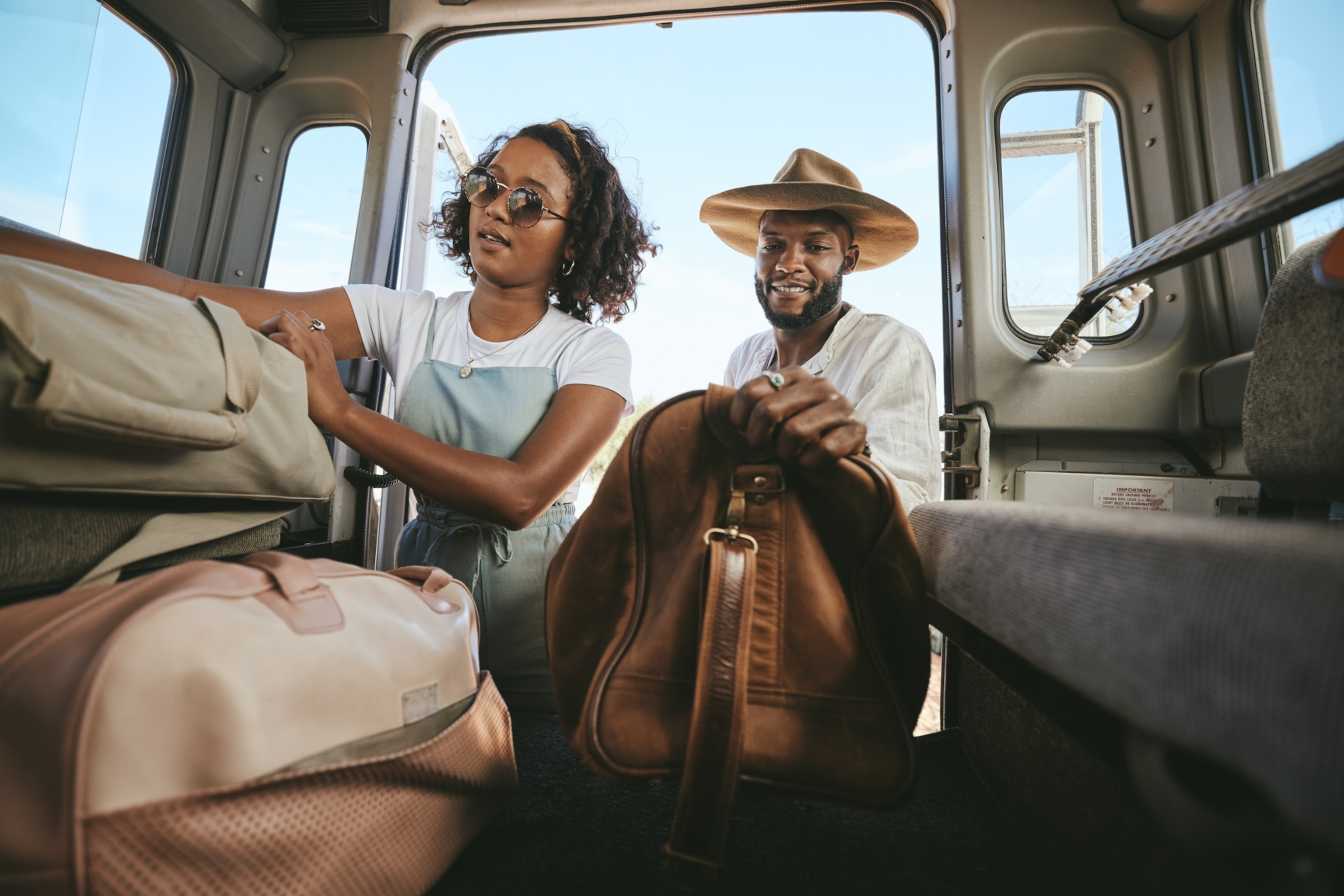 A black couple packing bags into the back of a van for road trip.