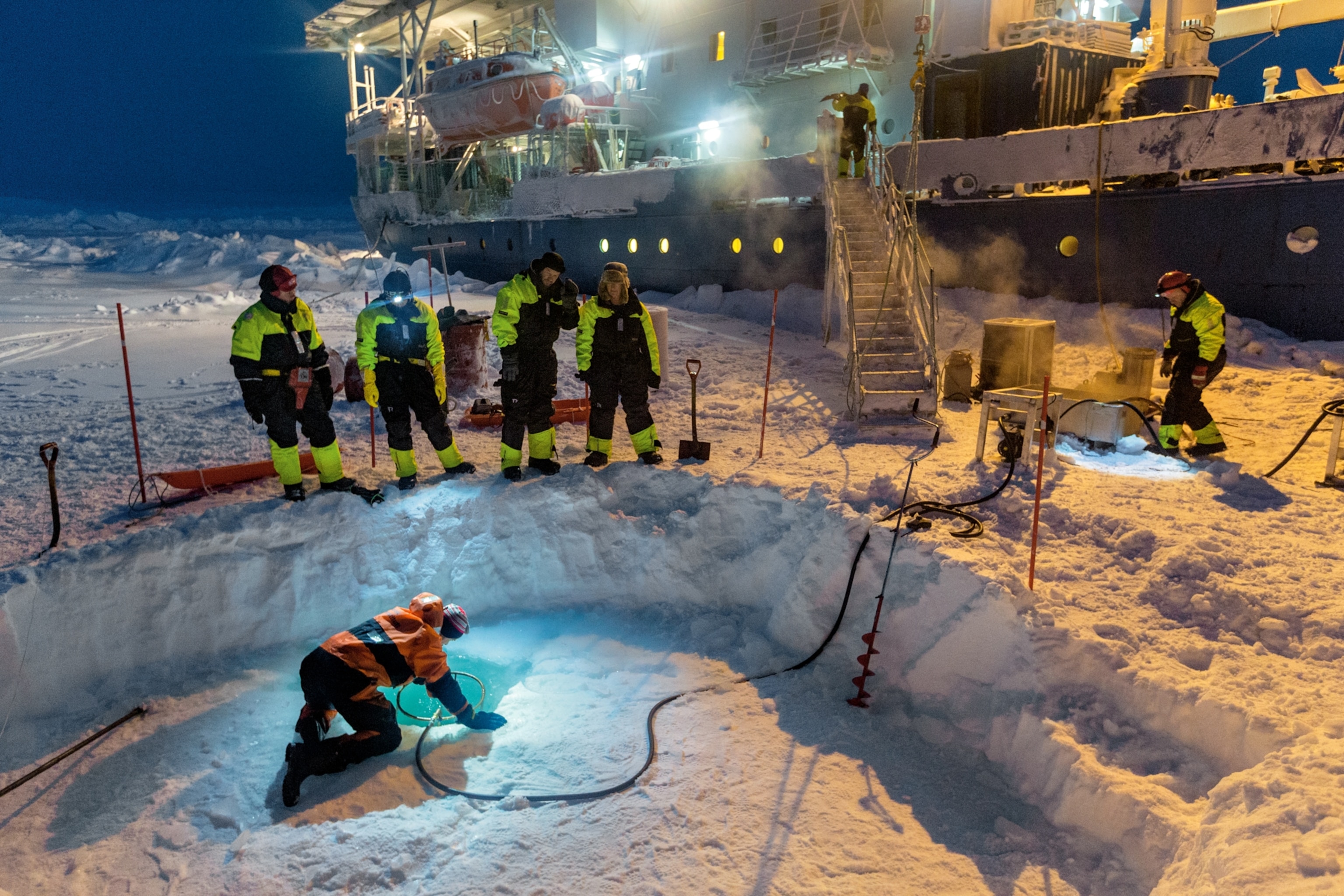 Scientists from the Lance melting a hole in Arctic ice