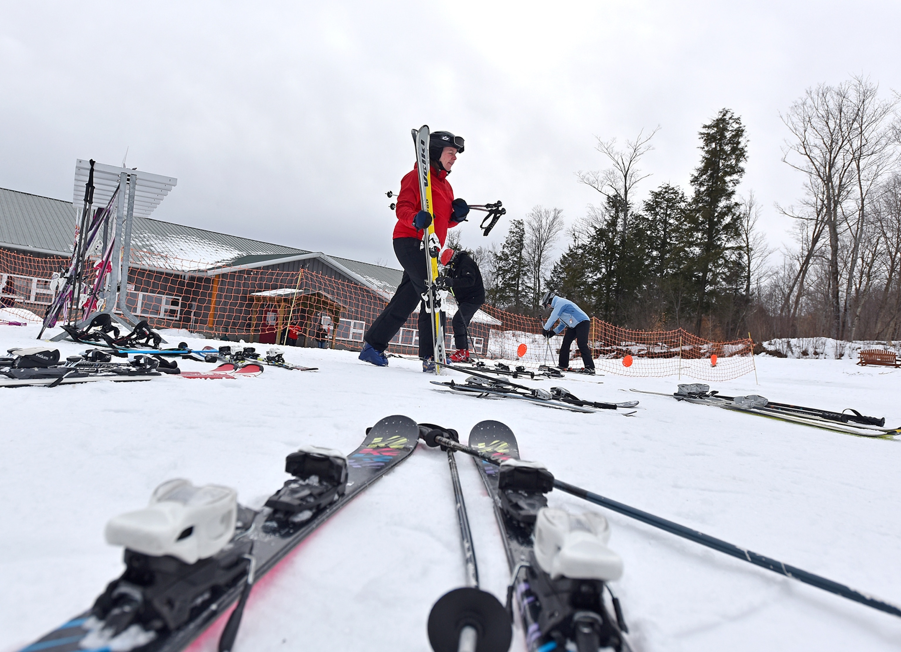 A skier walks across the snow while holding skis.