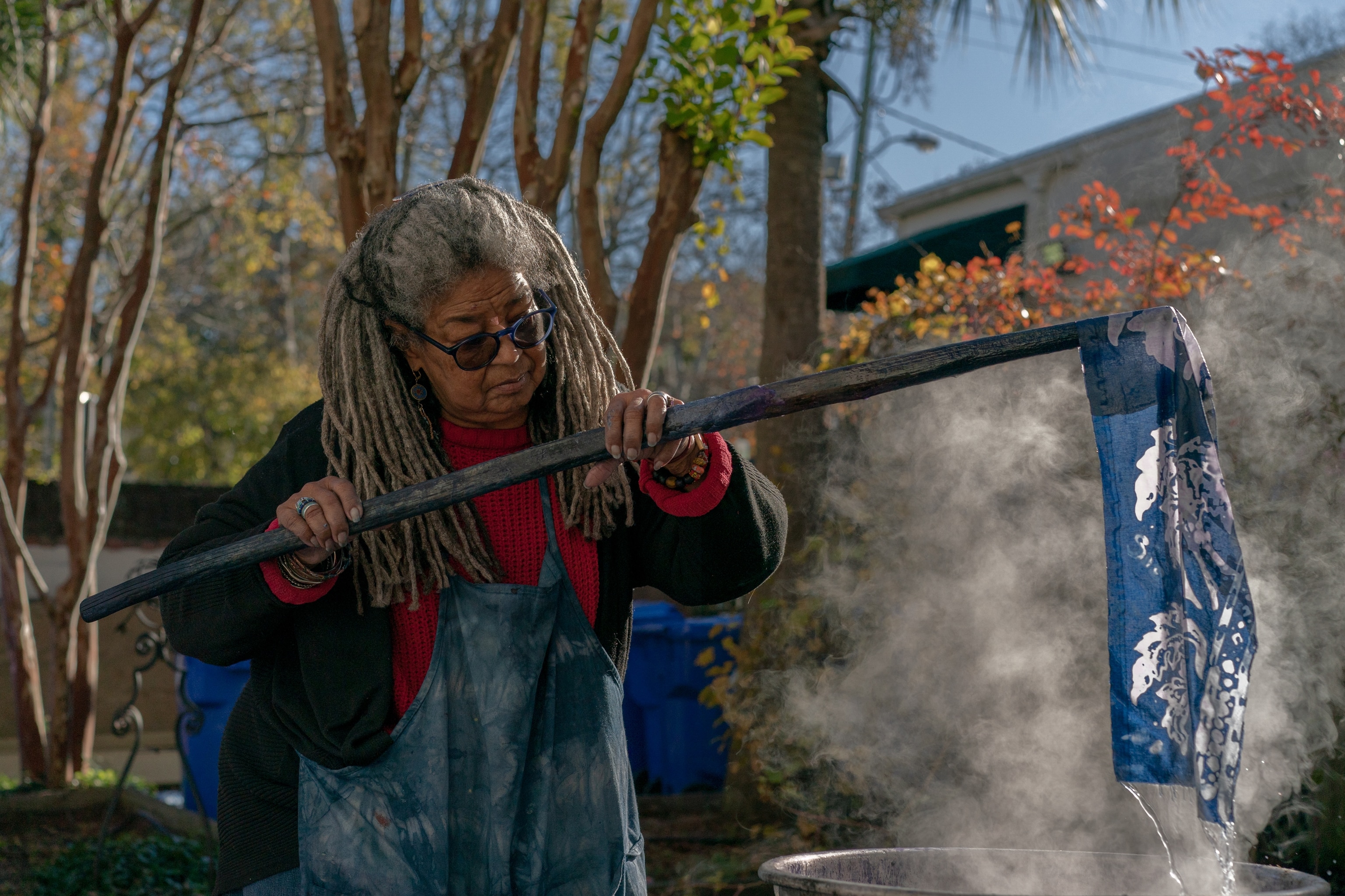 Arianne King Comer lifts a piece of indigo dyed batik fabric out of a vat of boiling water