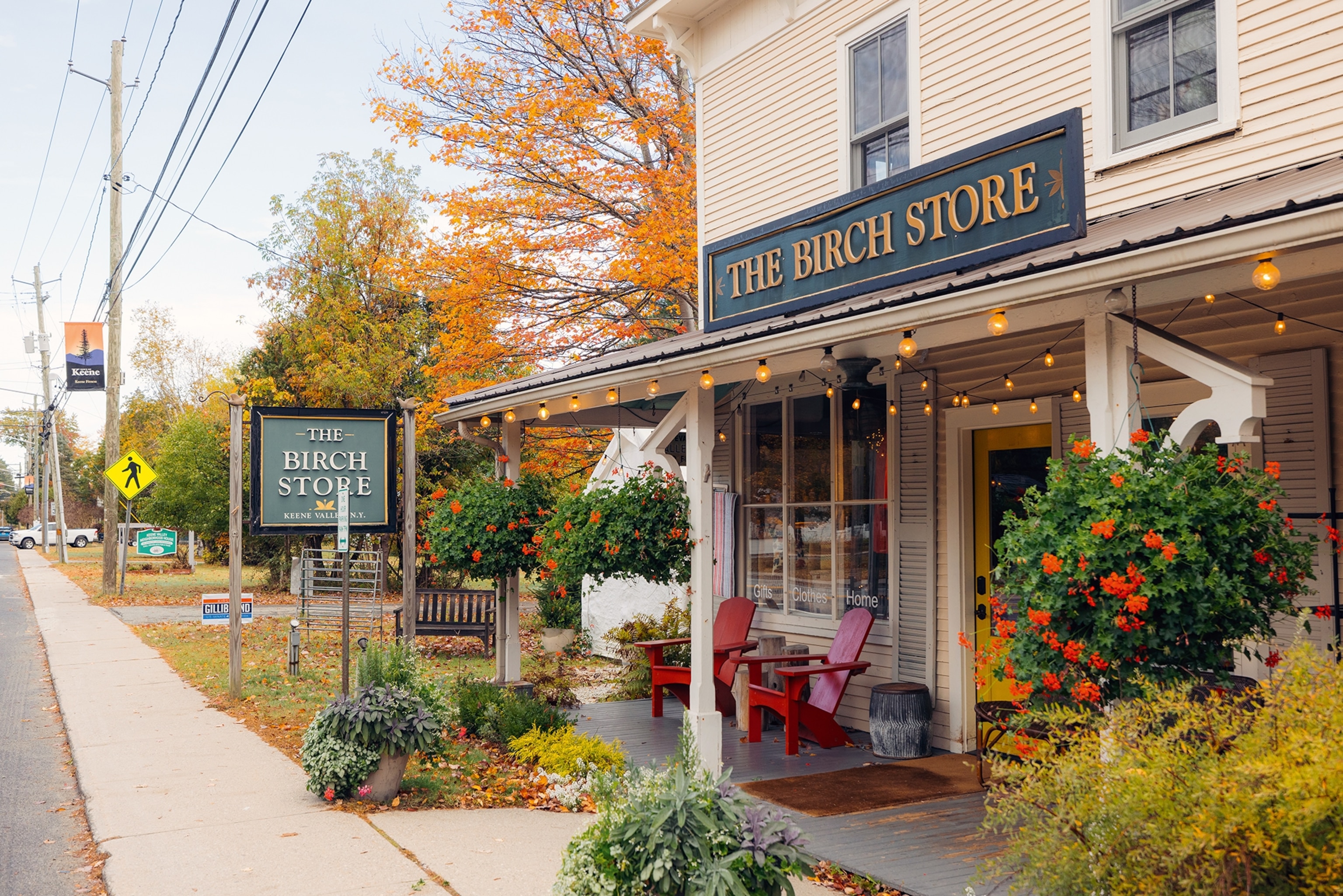 View on a traditionally American shop hugged by a porch with two chairs and fairy lights.
