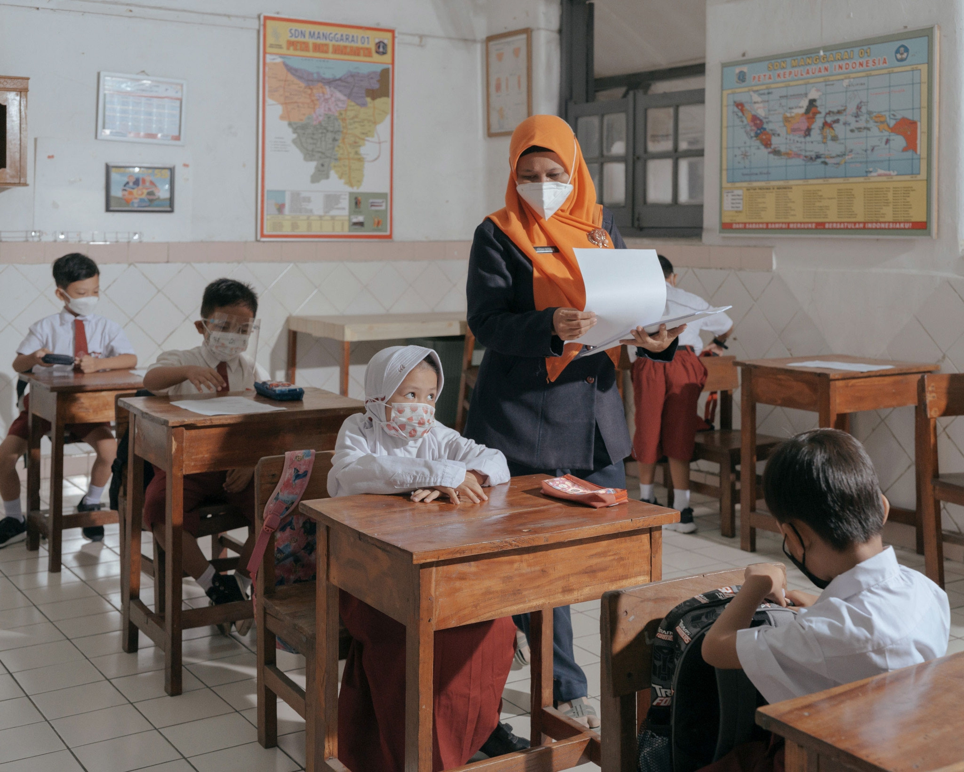 students attend class wearing masks in an elementary school in Indonesia