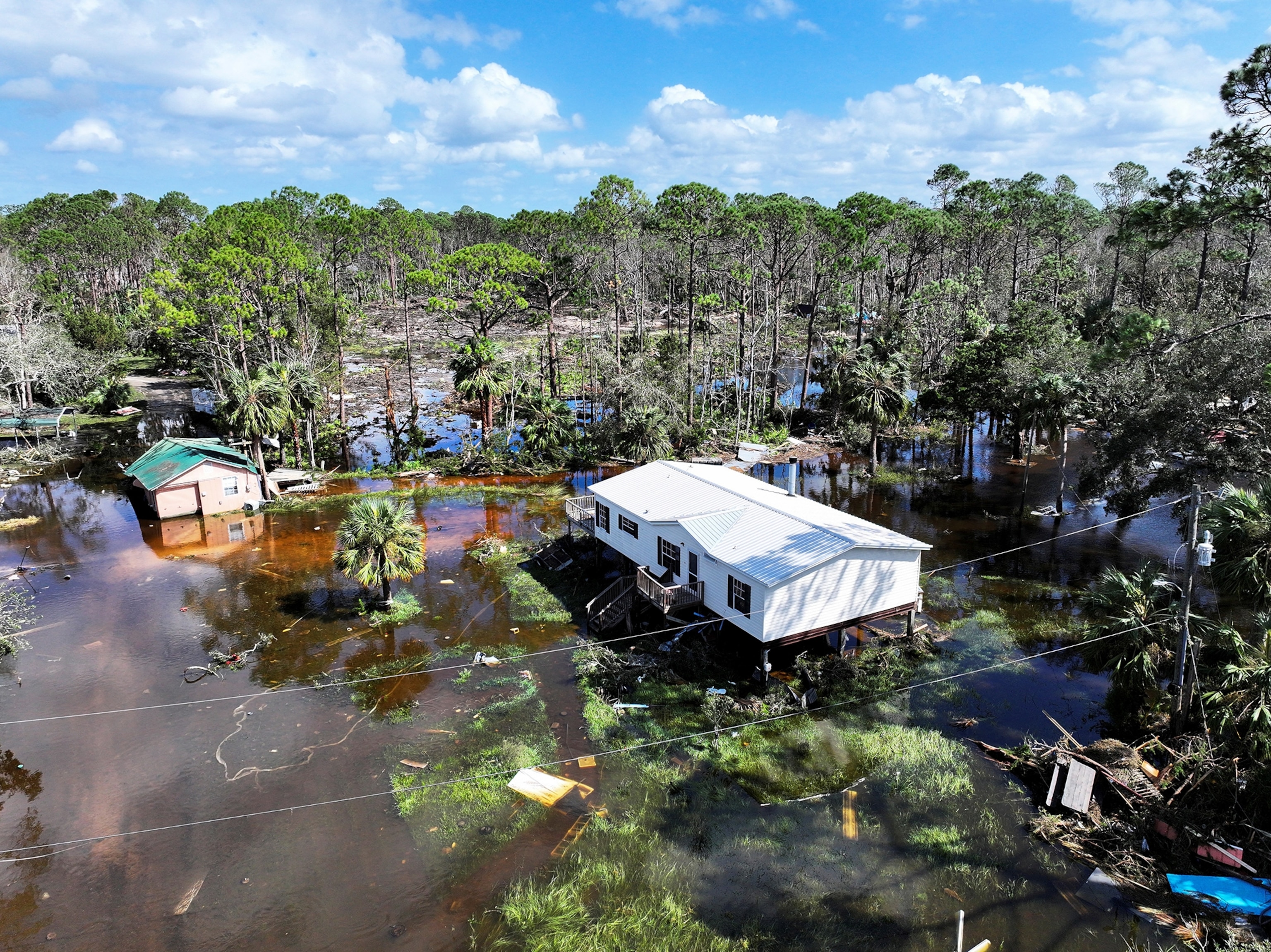 An aerial view of a white house in swampy dark waters.