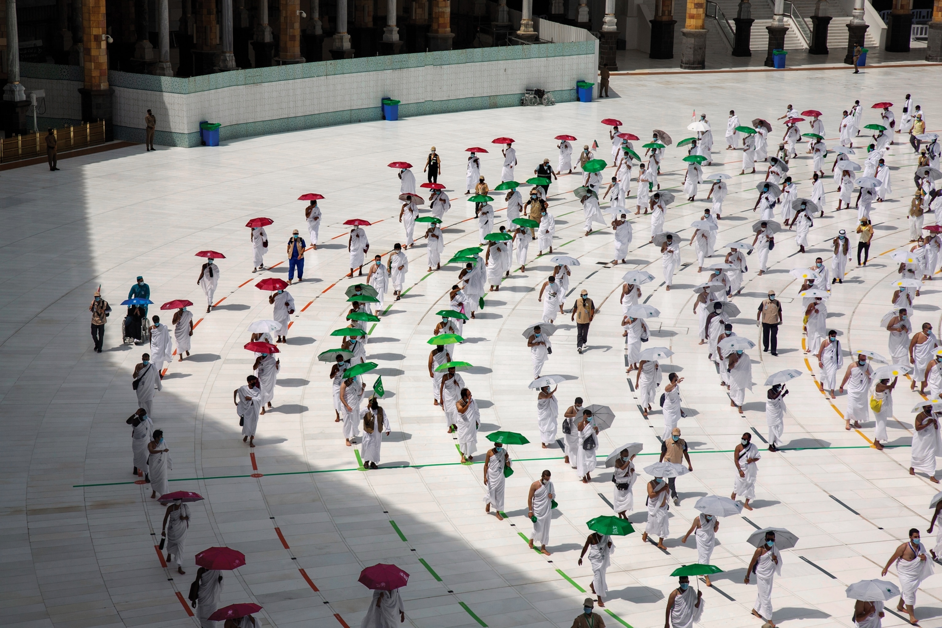 Picture of people in white clothes walking under umbrellas