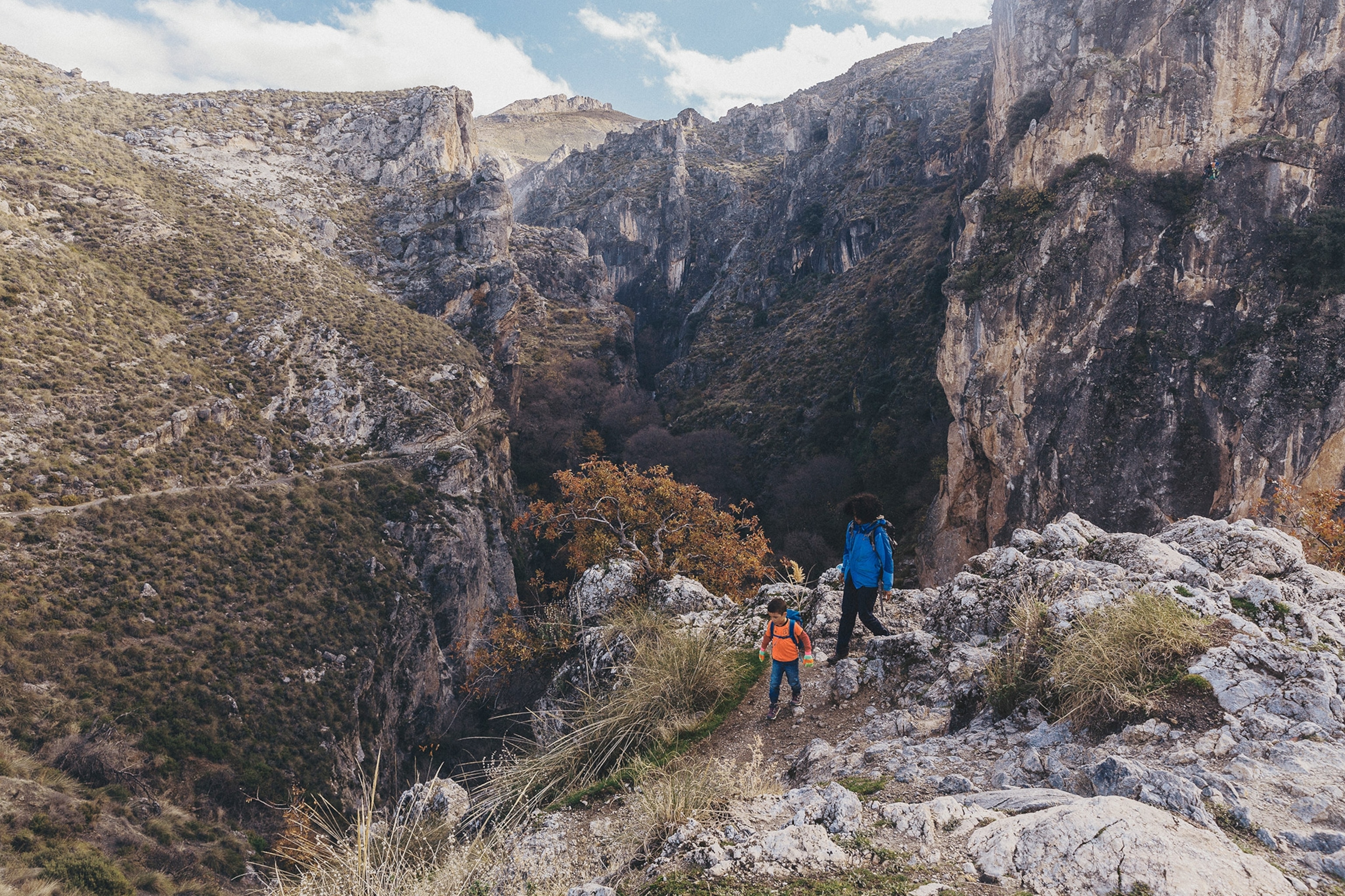 A woman and a child traverse a rocky path at the entrance to the dramatic Los Cahorros gorge near Monachil