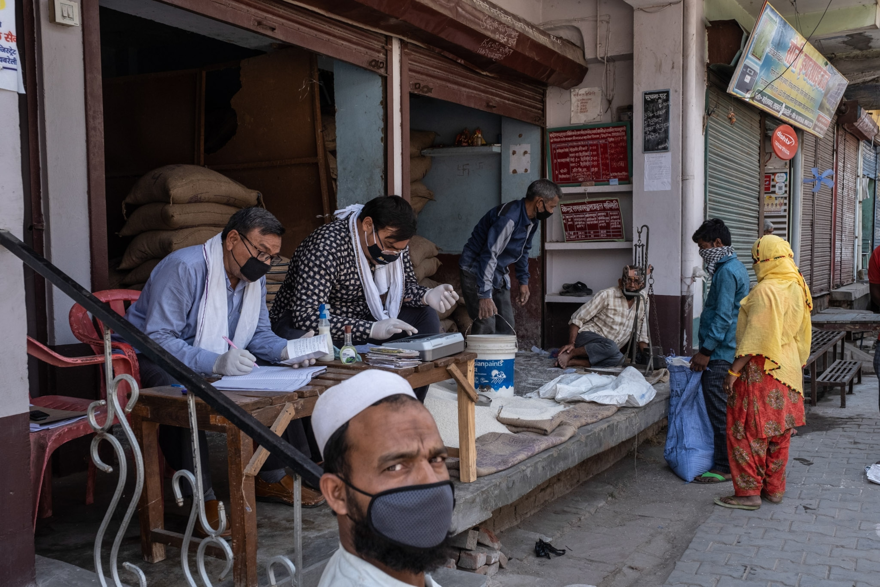 people standing outside of a shop, collecting food