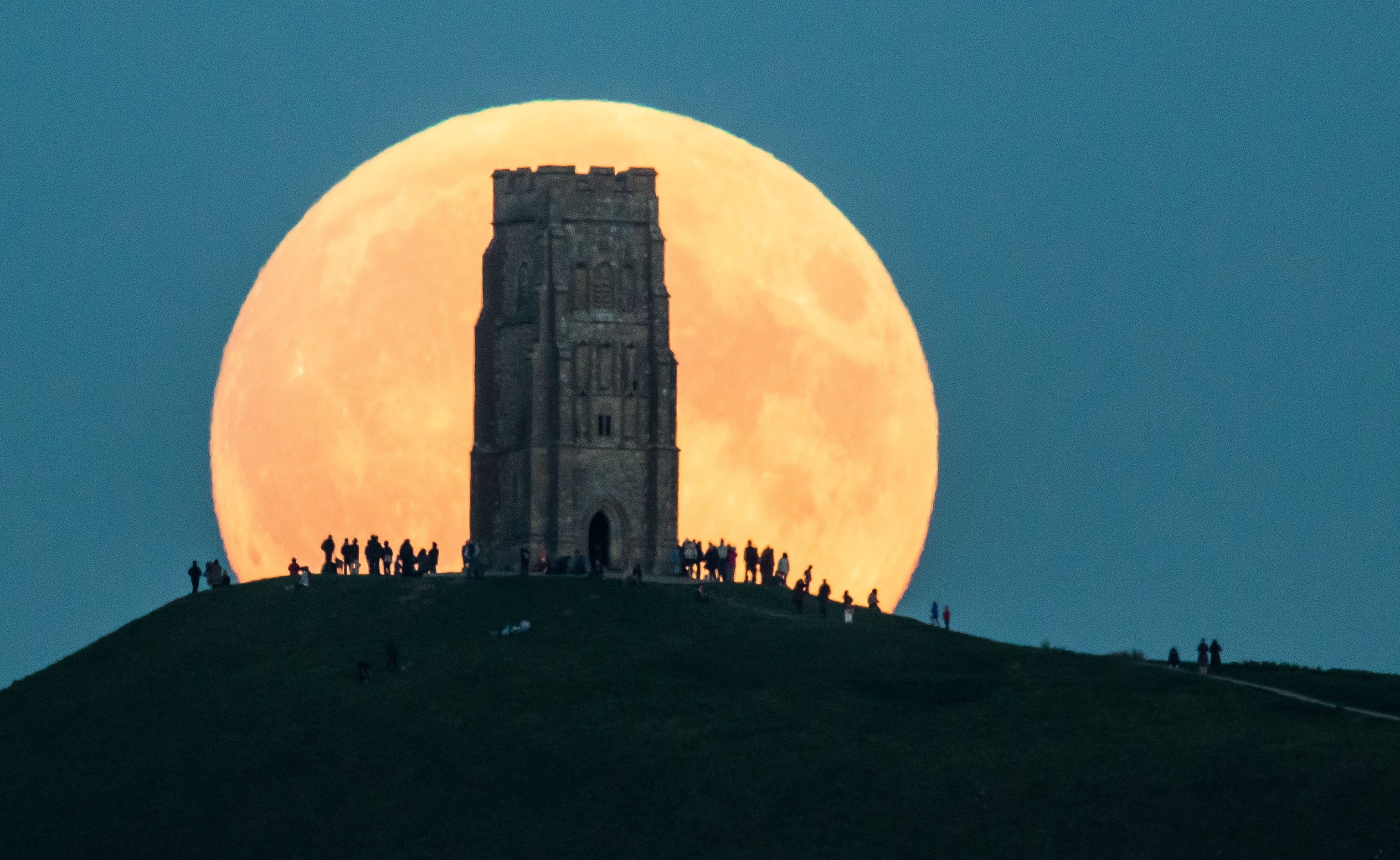Picture of a full moon rising behind Glastonbury Tor.