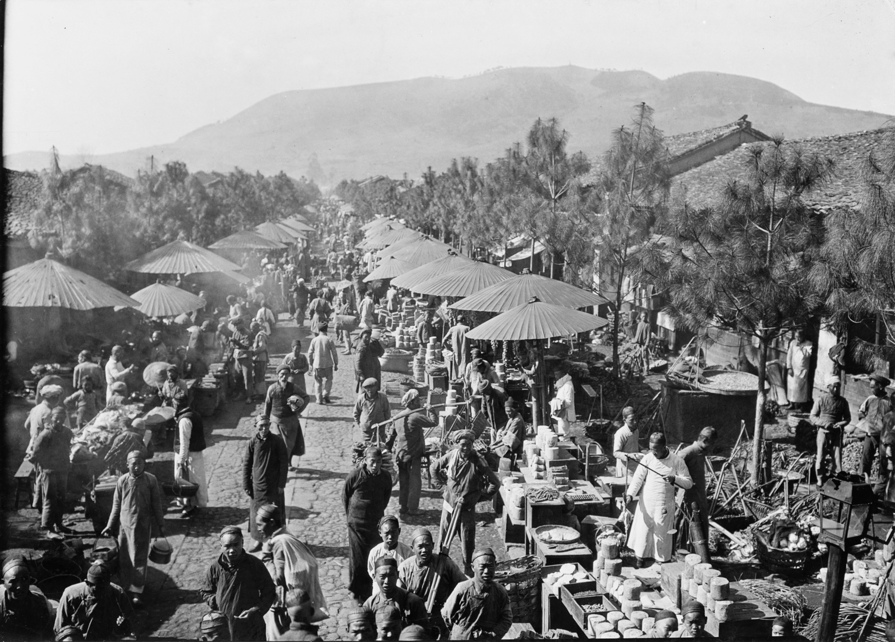 Photo of street with market stalls and umbrellas and mountains in distance
