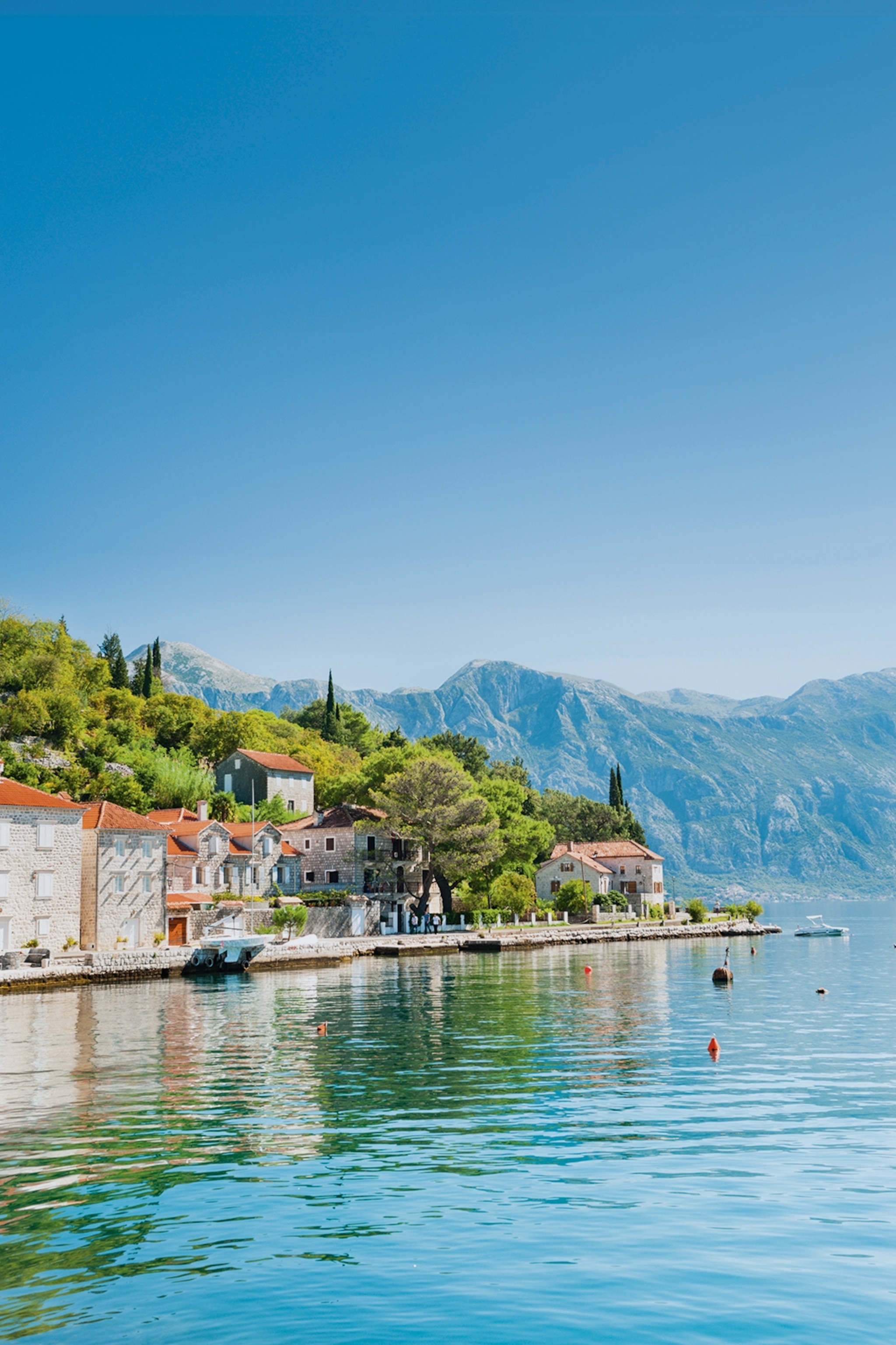Stone houses with red roofs positioned on the waterfront of turquoise sea